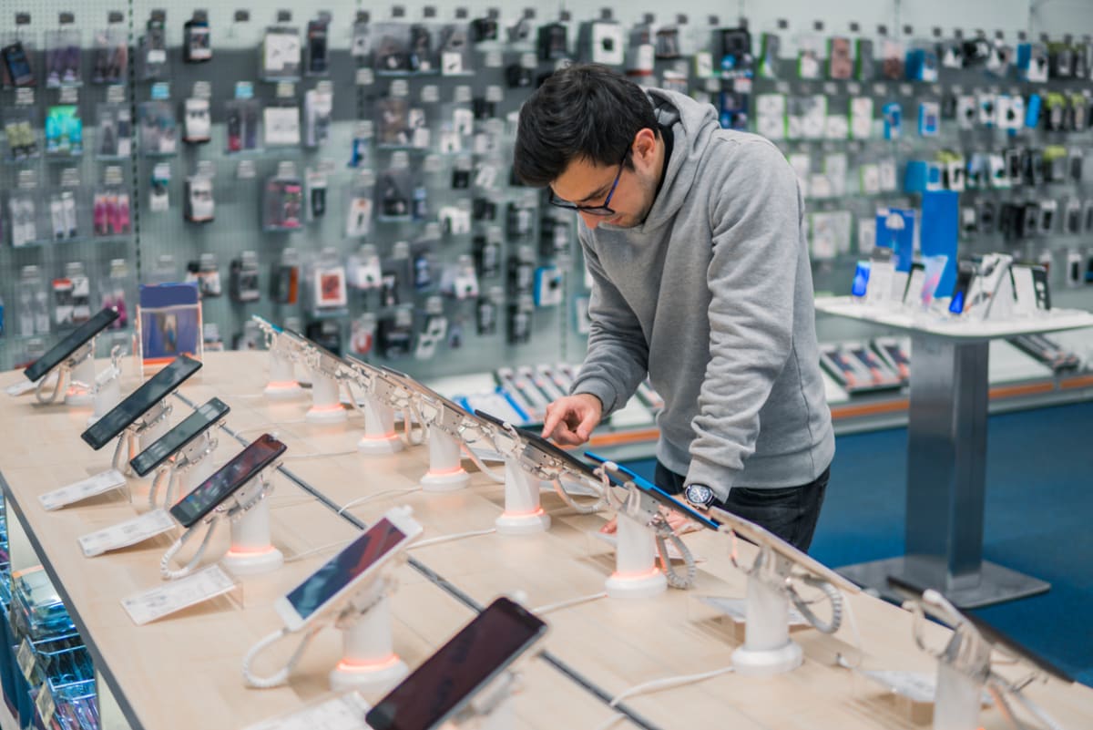 A man compares numerous phone models in a store.