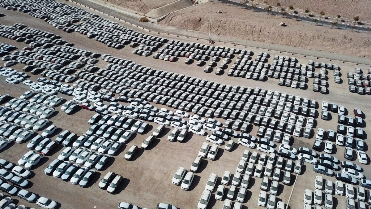 A photo of hundreds of new cars parked, waiting to be sold.