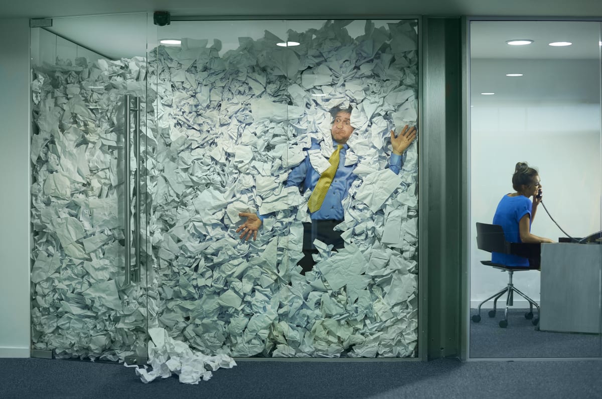 A person stuck in an office full of paperwork