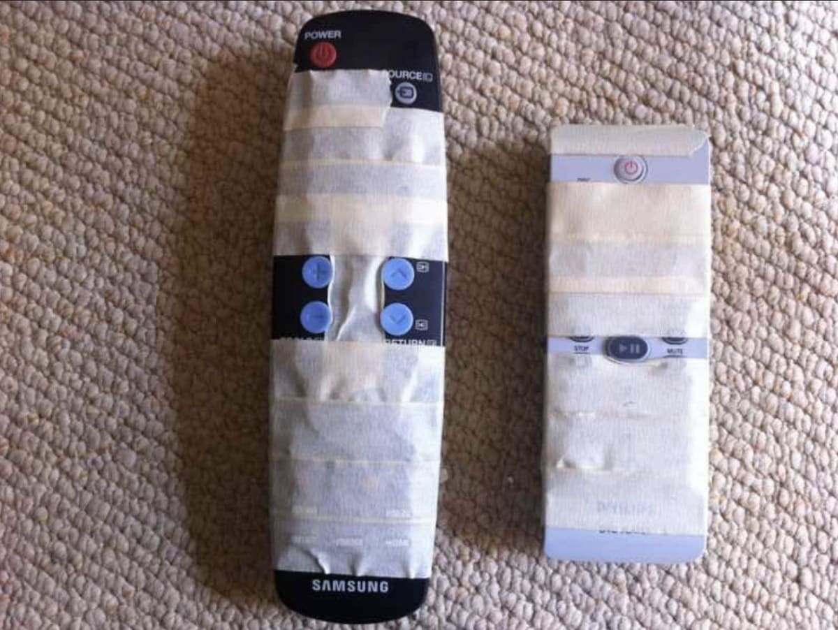 Two complex remote controls have been ‘fixed’ with the addition of masking tape, that covers all but the most essential buttons.