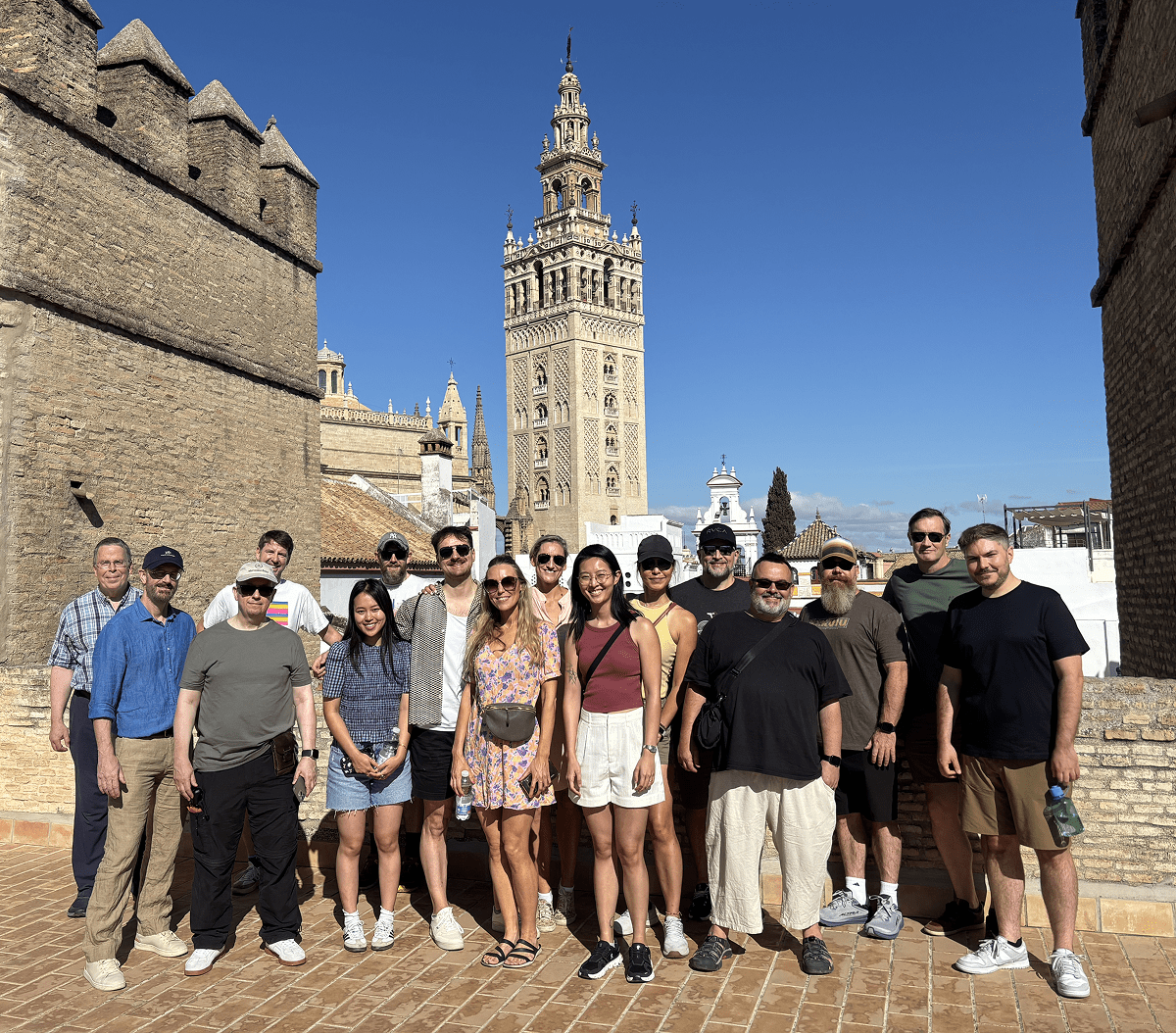 The CRE team posing together outdoors on a sunny day in front of the Giralda bell tower and historic buildings in Seville.