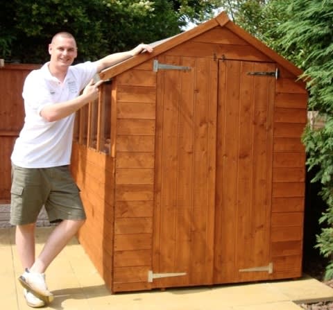 A photo of Ben next to his assembled shed.