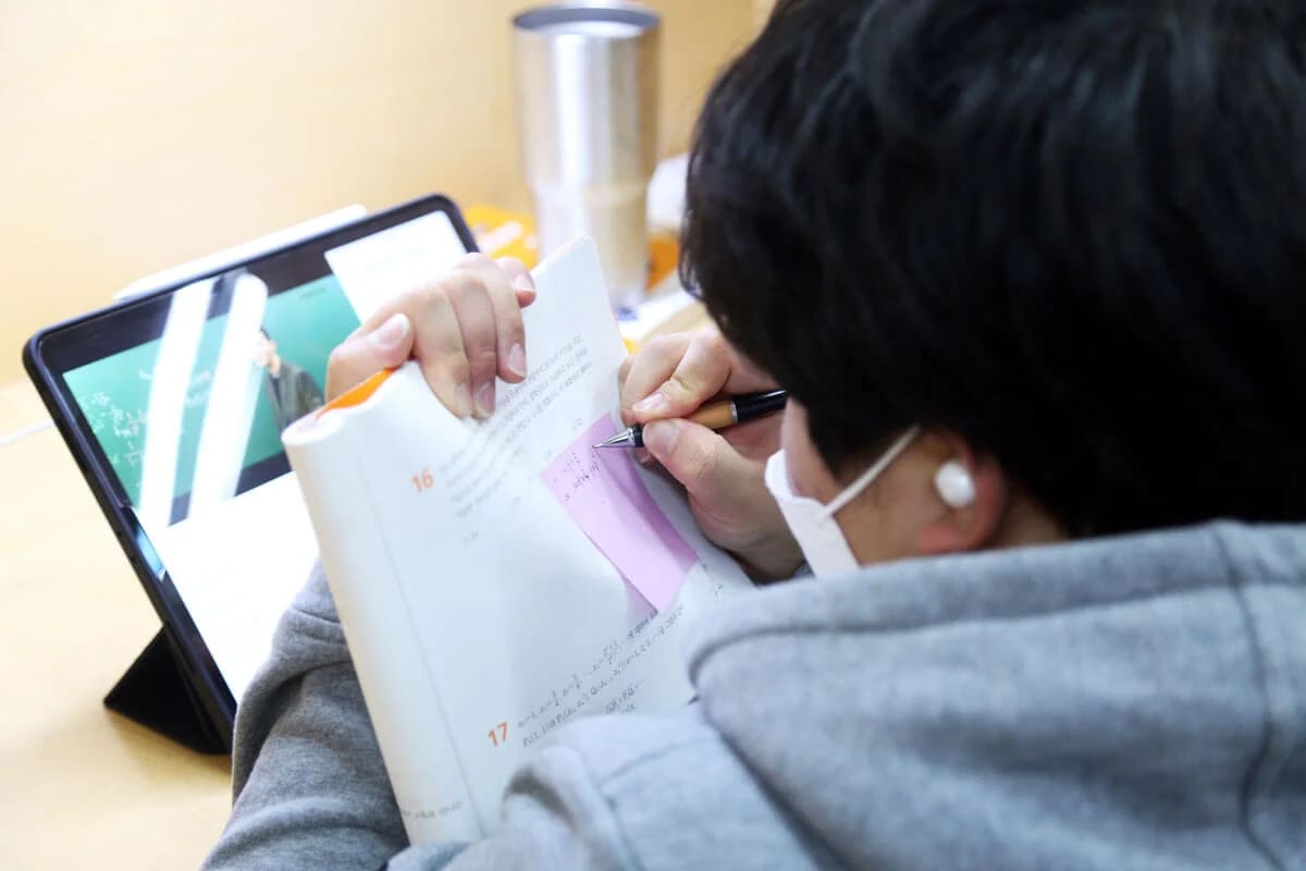 남학생 캠퍼스에서 태블릿으로 학습하는 모습