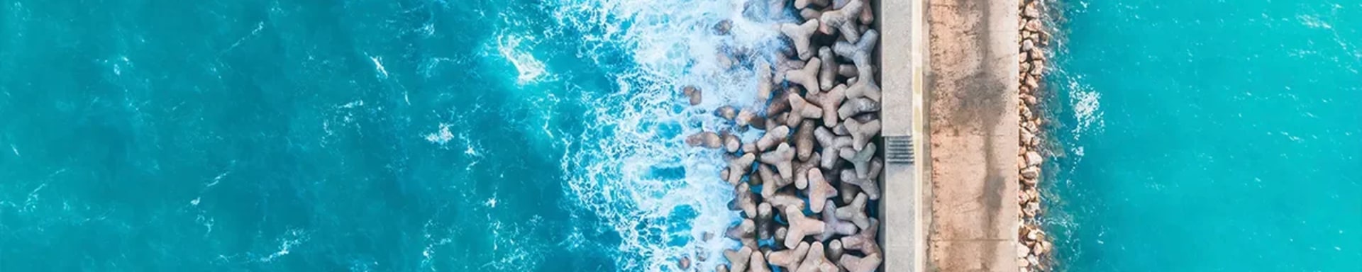 Bird's eye view of an ocean divided by manmade passage in the middle of it and enforced by large rocks