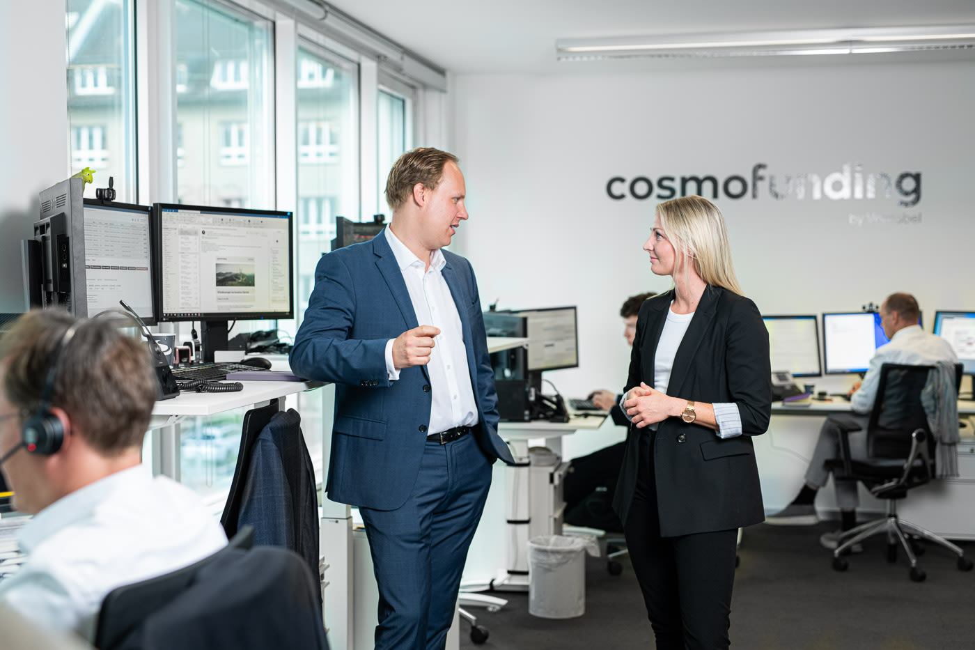 Deux employés masculins de Cosmofunding discutent dans un bureau.
