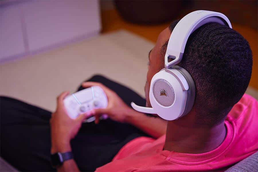 A male gamer sitting back playing games on his console while wearing the HS65 WIRELESS gaming headset.