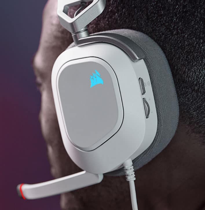 Man wearing HS80 RGB USB wired gaming headset plays a game with RGB lights on the CORSAIR sailboat logo on.