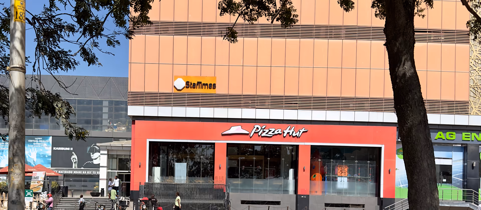 Ein Gebäude mit einem Pizza-Hut-Laden an einer Straße, gesehen zwischen Bäumen.