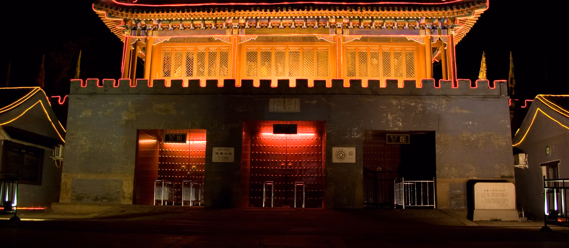 Nachtaufnahme eines beleuchteten traditionellen chinesischen Torbaus.