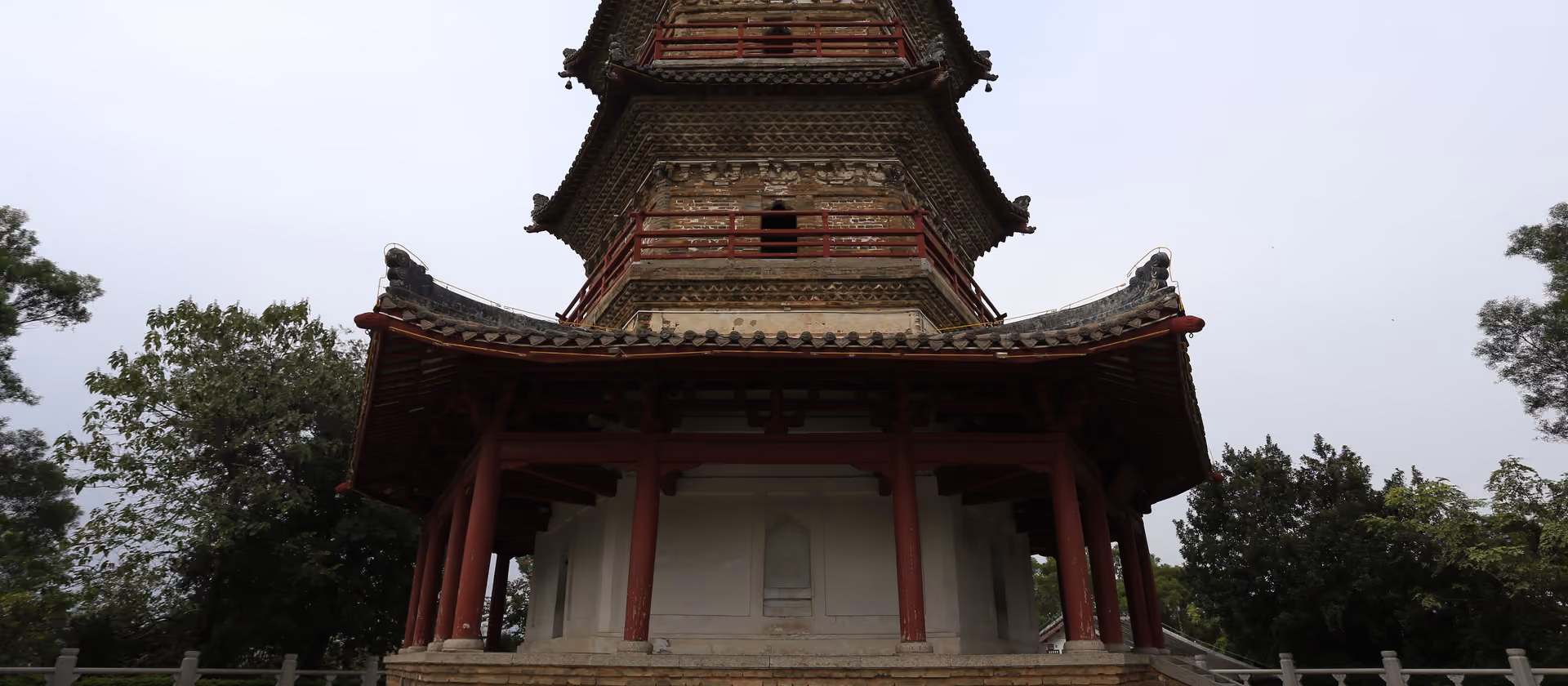 Eine traditionelle mehrstöckige Pagode mit roten Geländern und Ziegeldach, von unten gesehen.