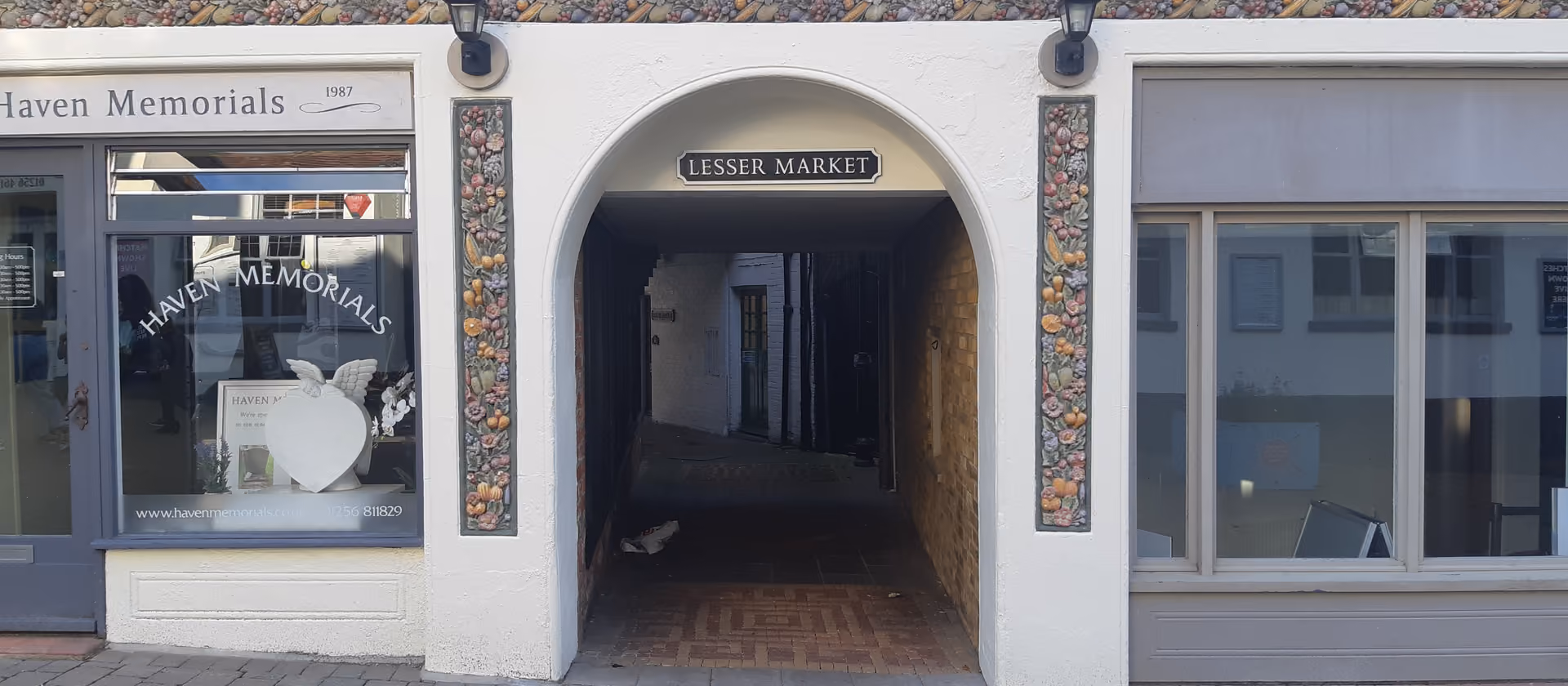 Ein Durchgang mit der Beschilderung „Lesser Market“ zwischen Ladenfronten.