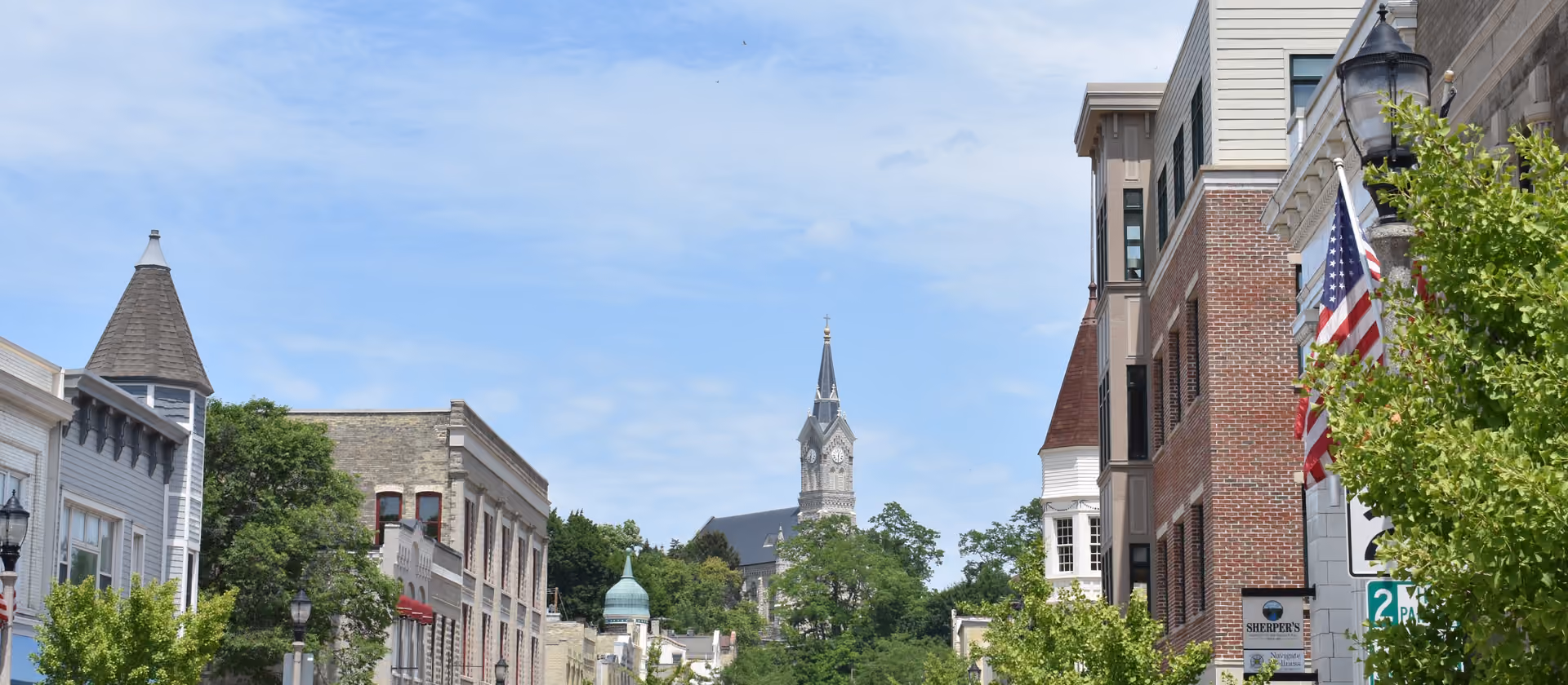 Straße in der Innenstadt mit Gebäuden und einem Kirchturm im Hintergrund.