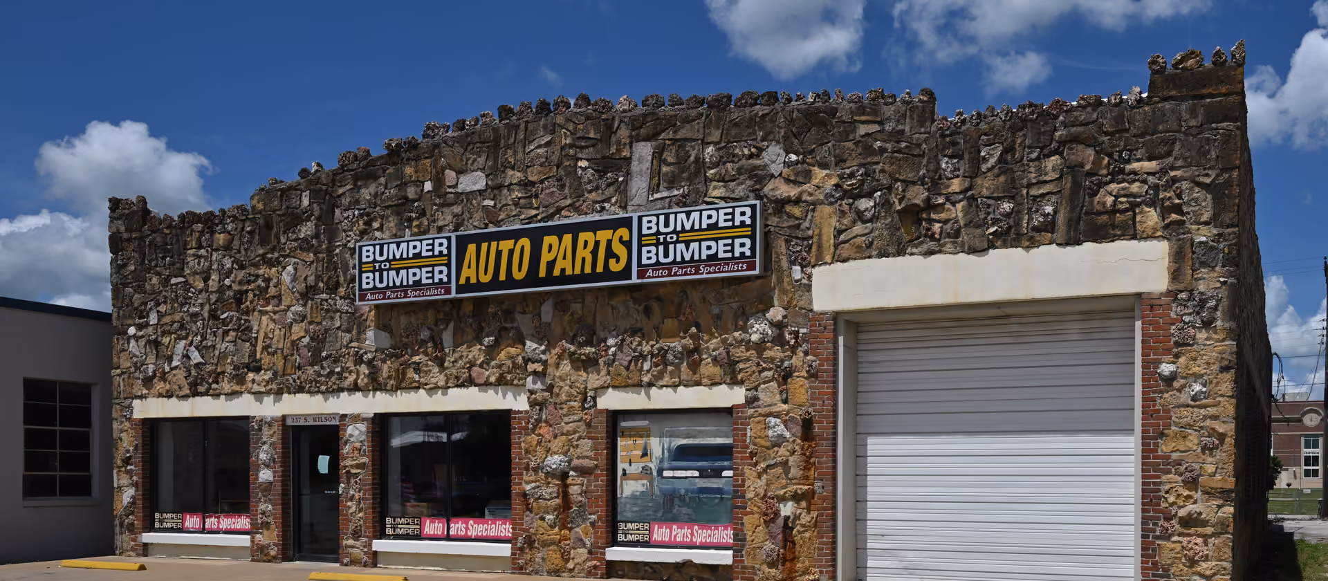 Ein steingefasstes Geschäftsgebäude mit der Aufschrift „Bumper to Bumper Auto Parts“ unter blauem Himmel.