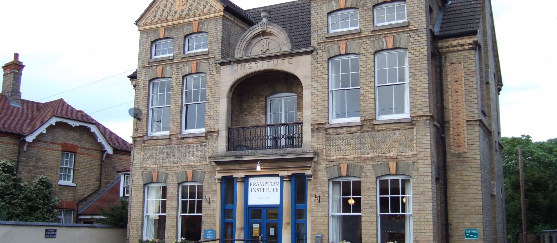 Backsteingebäude des Brampton Institute mit blauem Eingang und Sprossenfenstern.