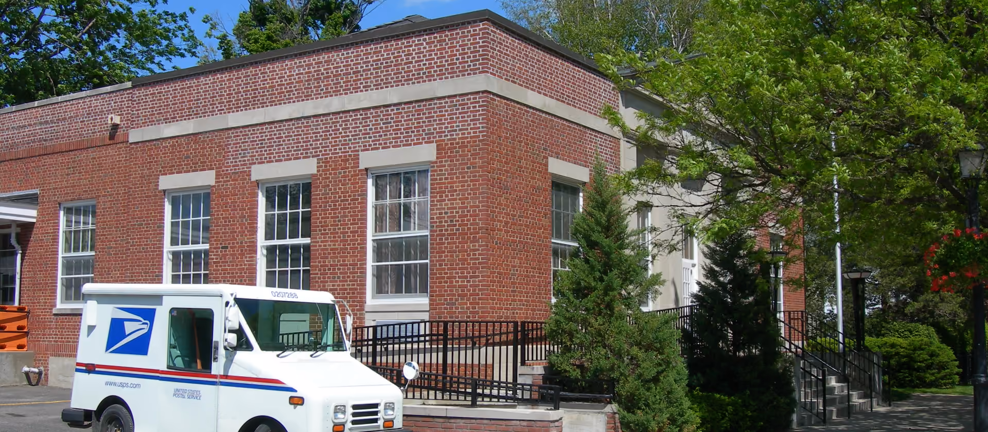 Backsteingebäude der Post in Cooperstown mit einem USPS-Transporter davor.