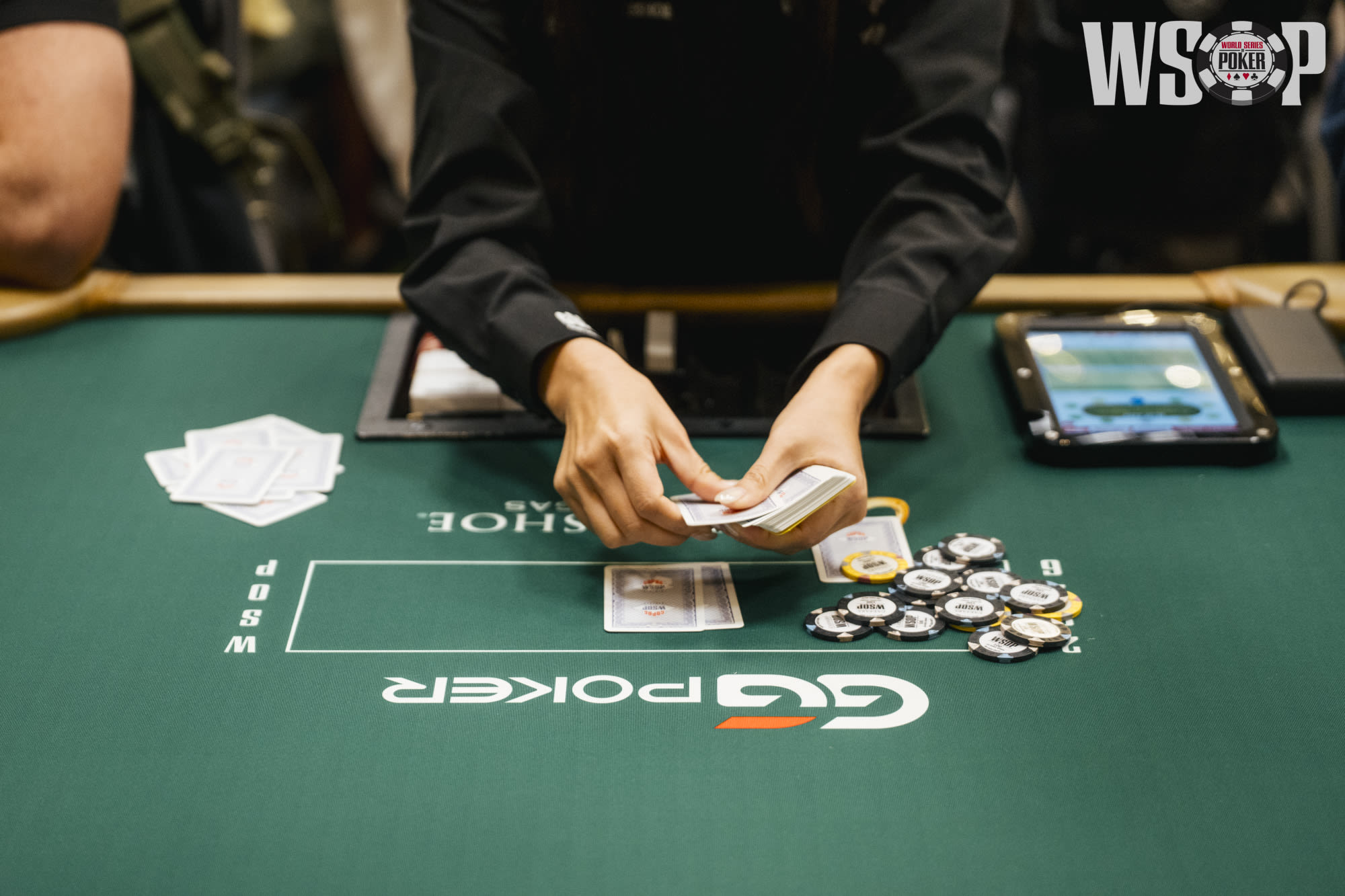 Dealer repartiendo cartas cerca del paño en una mesa de poker en vivo