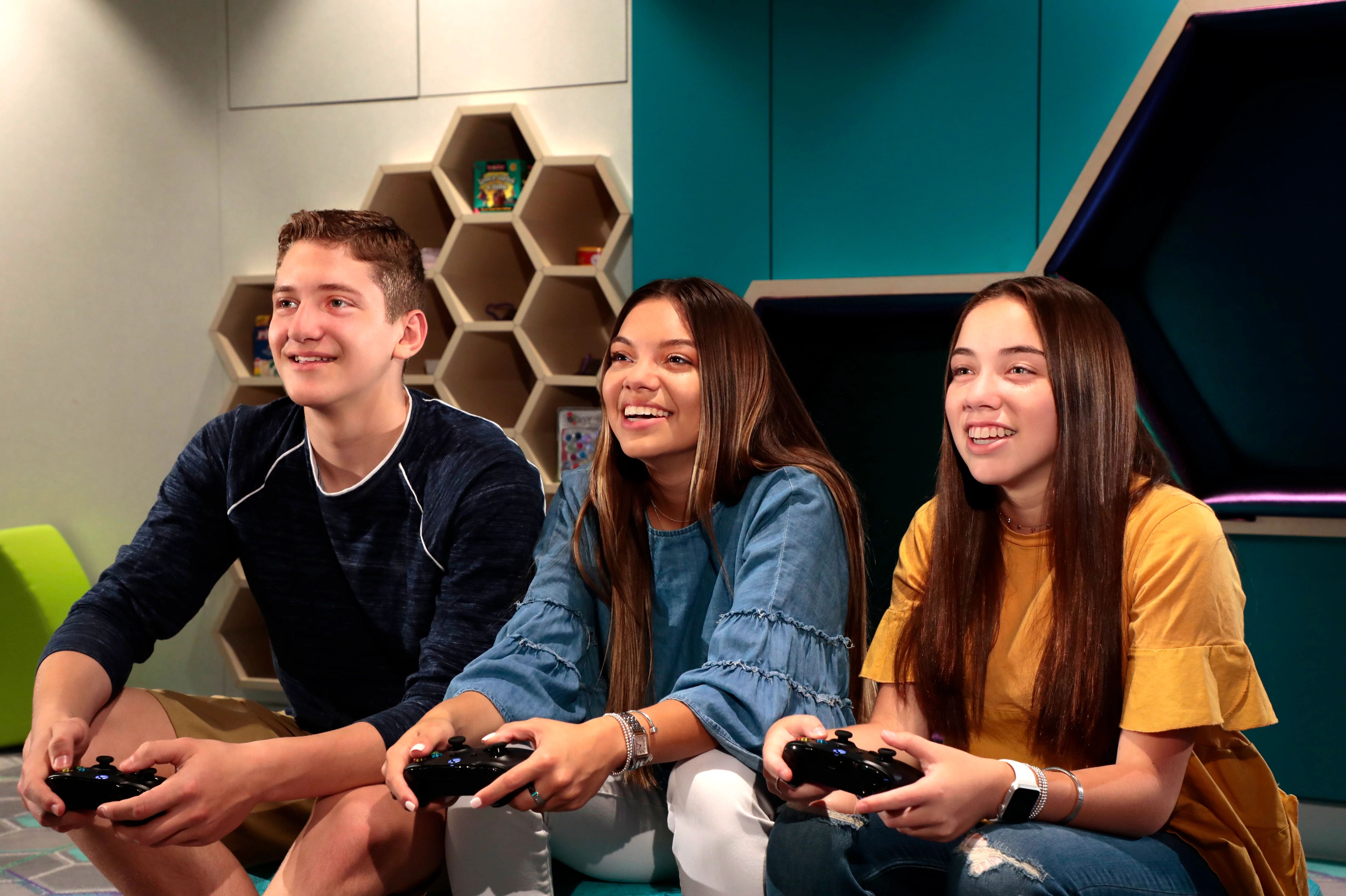 Teenagers enjoying video games in the Recreation area on a cruise ship, with a vibrant and modern design.