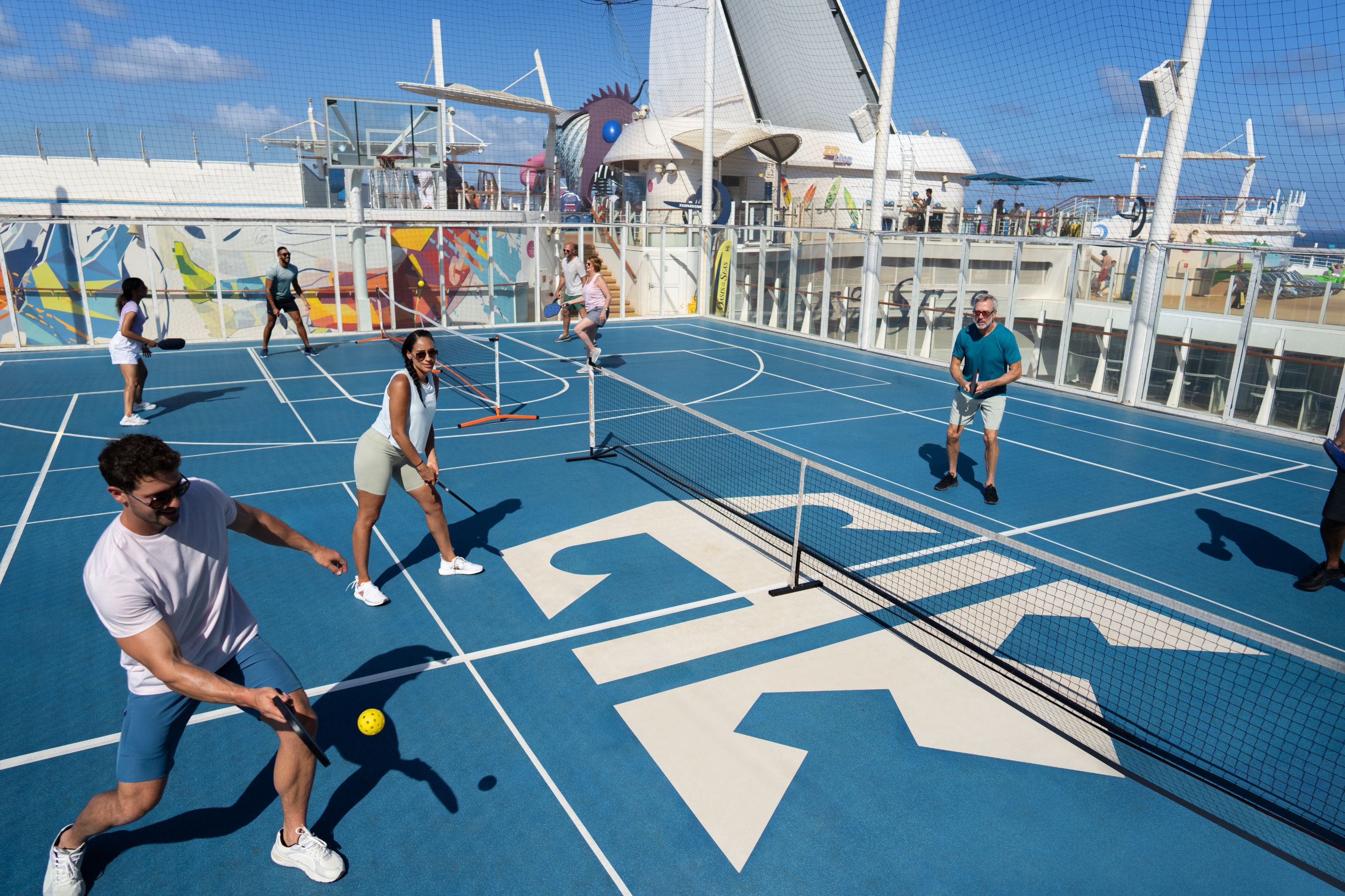 Guests enjoying a game of pickleball on Oasis of the Seas' sports court with ocean views.