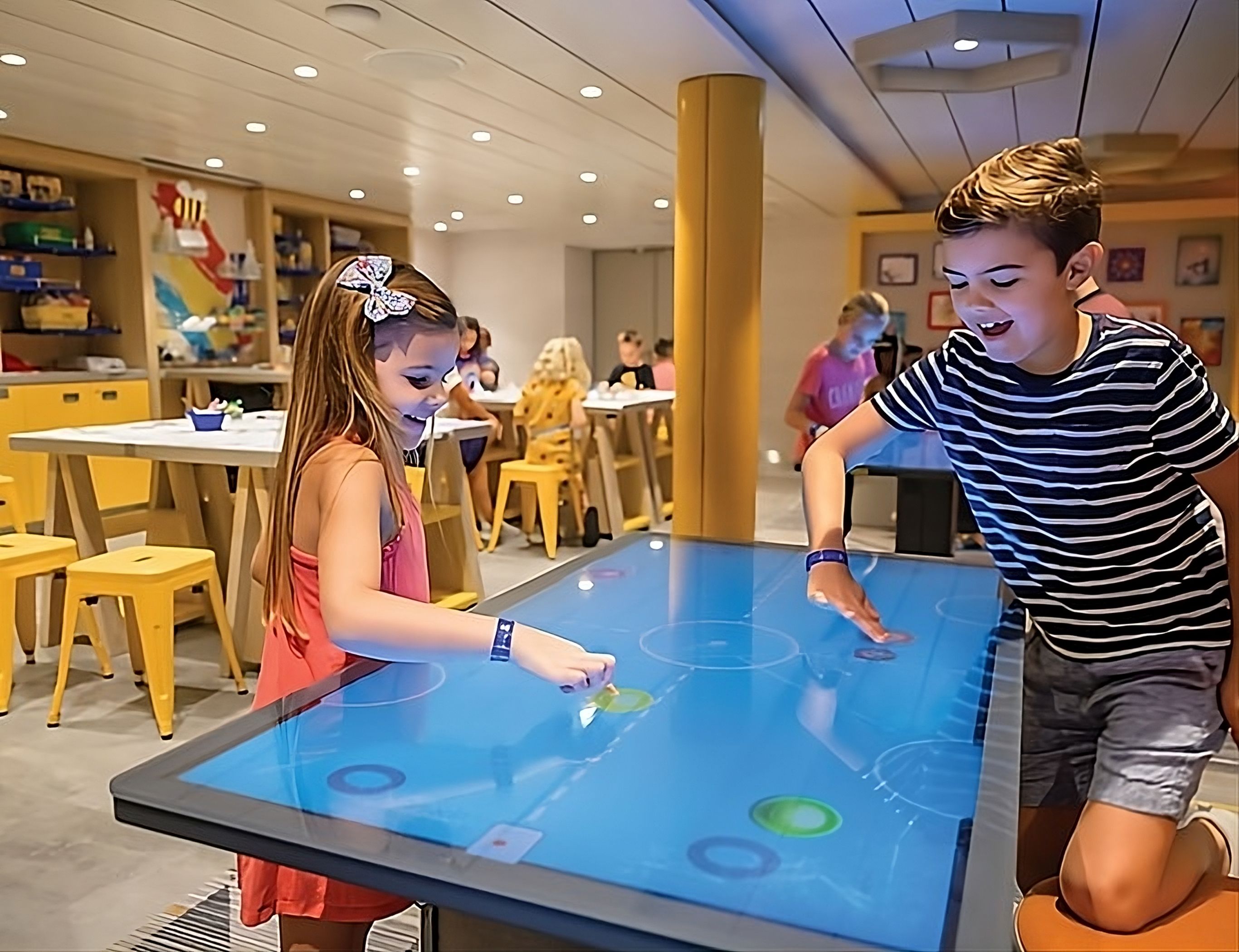 Children enjoying interactive digital game table at Royal Caribbean's Adventure Ocean youth facility.