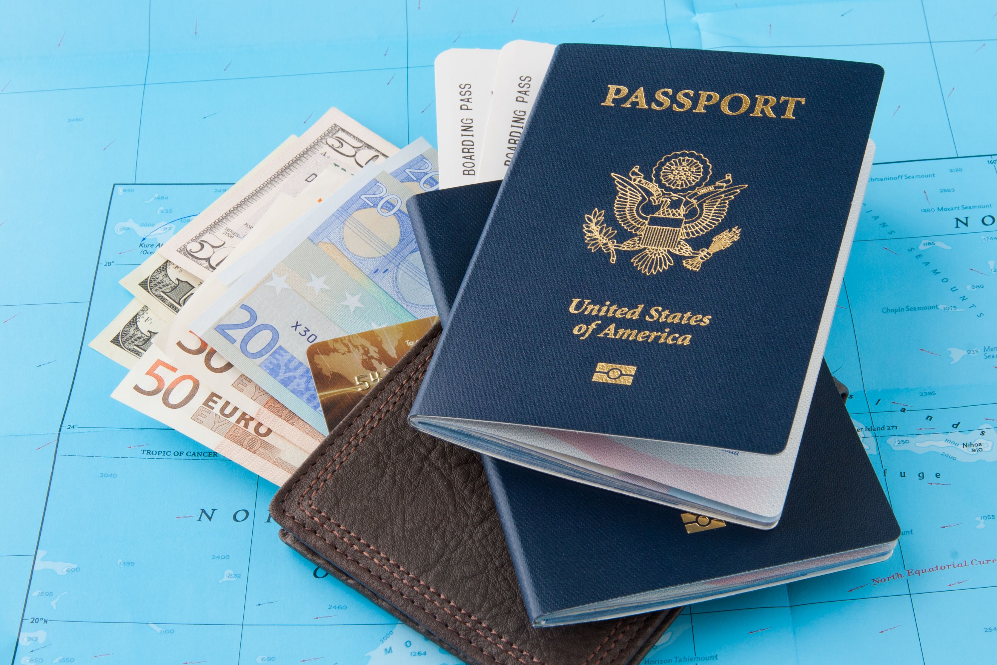 US passport, boarding pass, wallet, and mixed currency on a map, essentials for a 7-day cruise to Mexico.