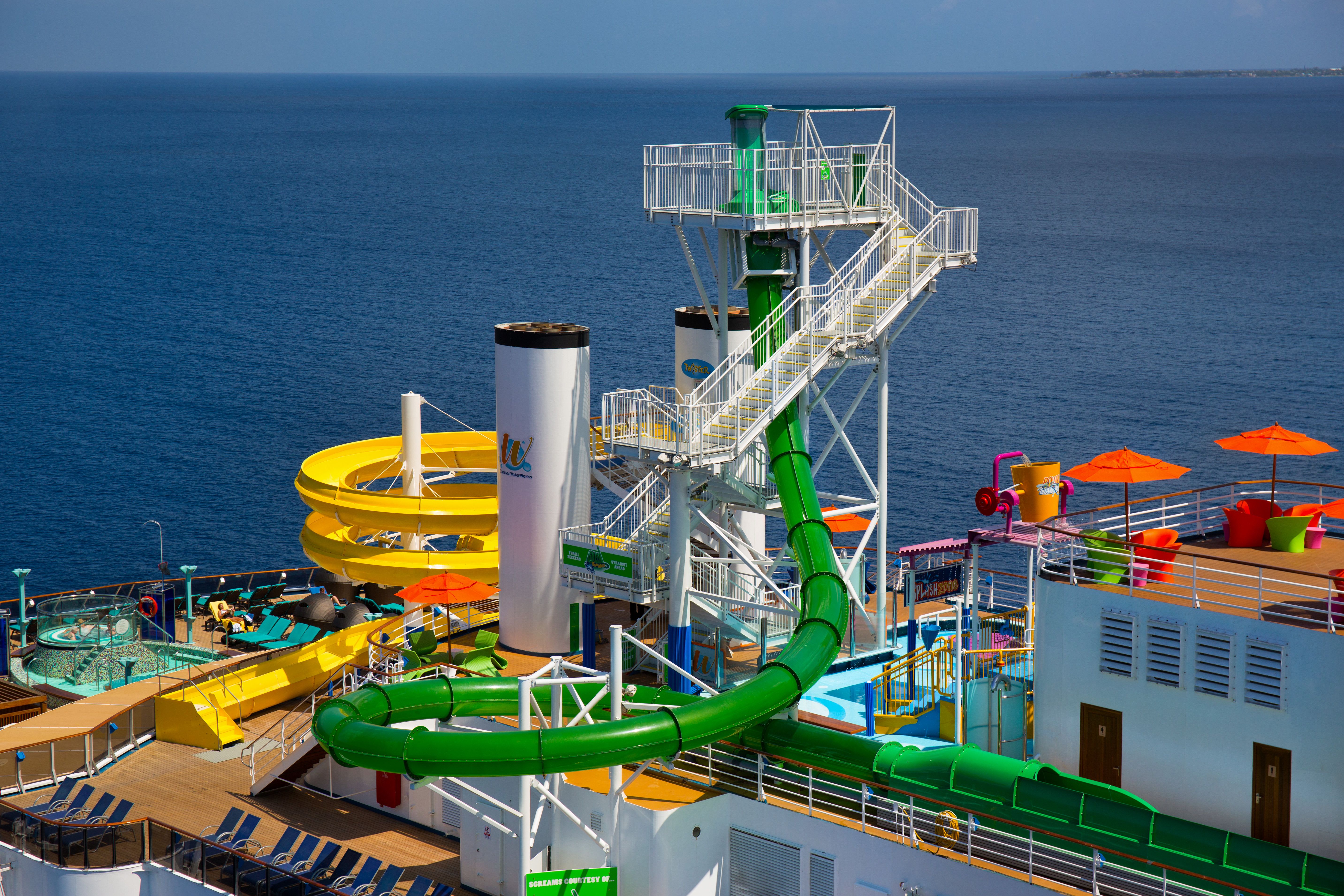 Carnival Legend's water slides tower above the deck, set against the backdrop of a calm blue sea.