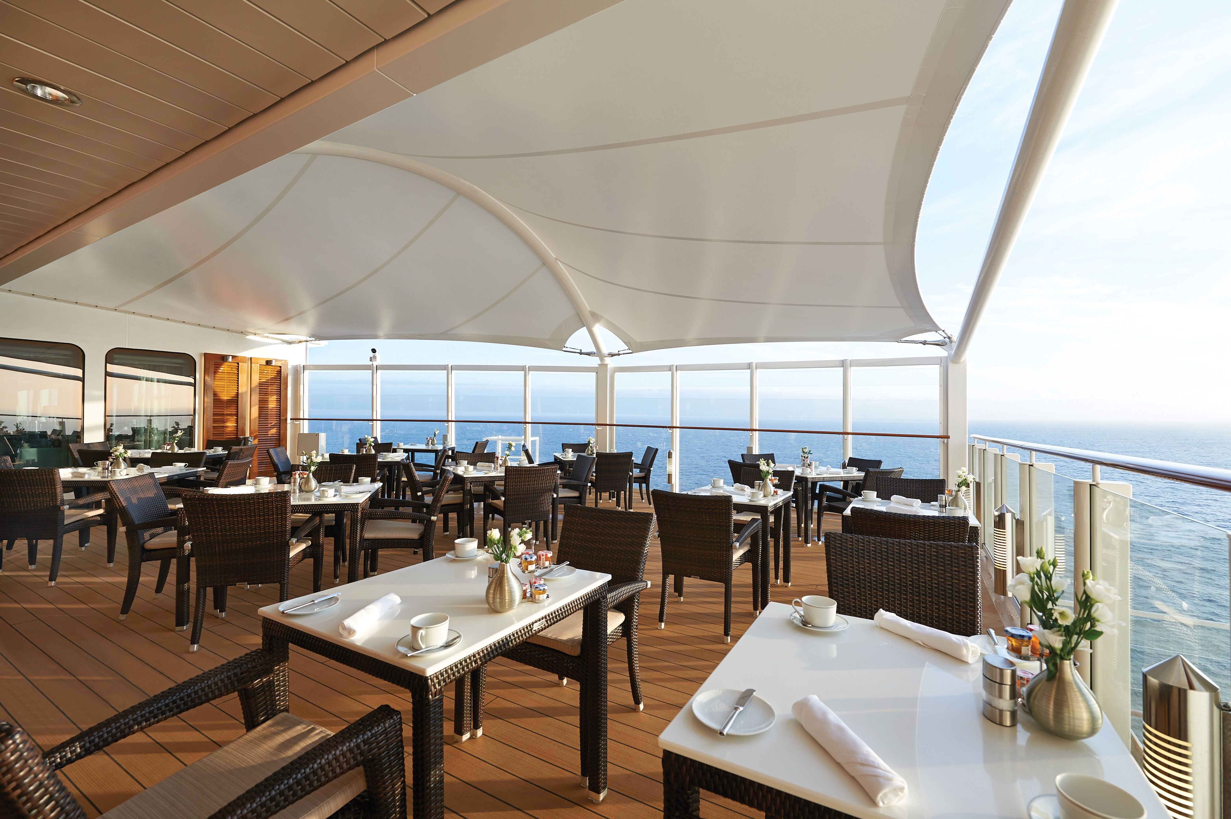 The Haven Restaurant on Norwegian Bliss offers al fresco dining with elegant wicker furniture and unobstructed ocean views for an exclusive, upscale experience.