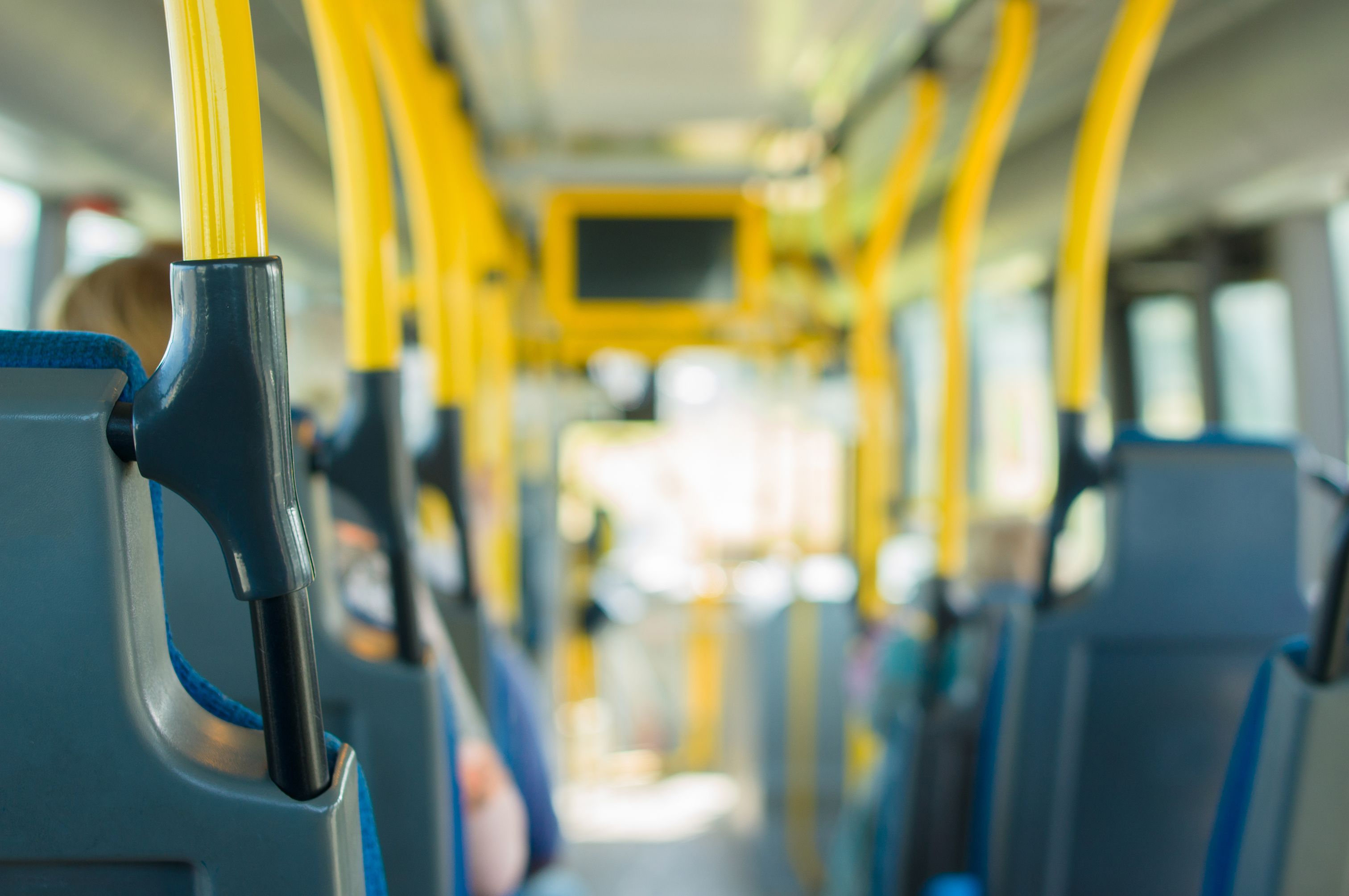 Interior view of a city bus with bright yellow grab bars, providing public transportation to the cruise terminal.