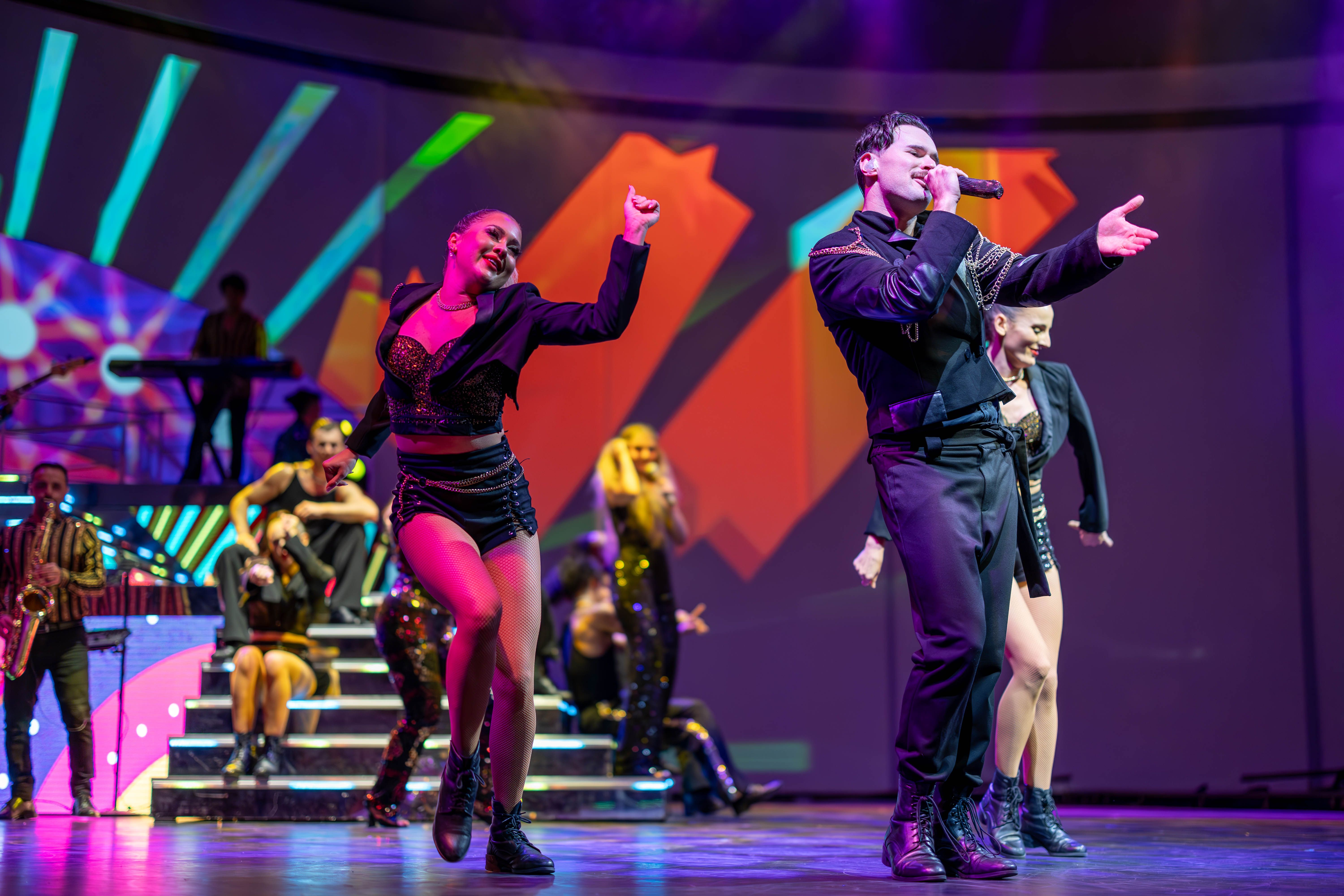 Vibrant cruise ship entertainment show with dancers and singer.