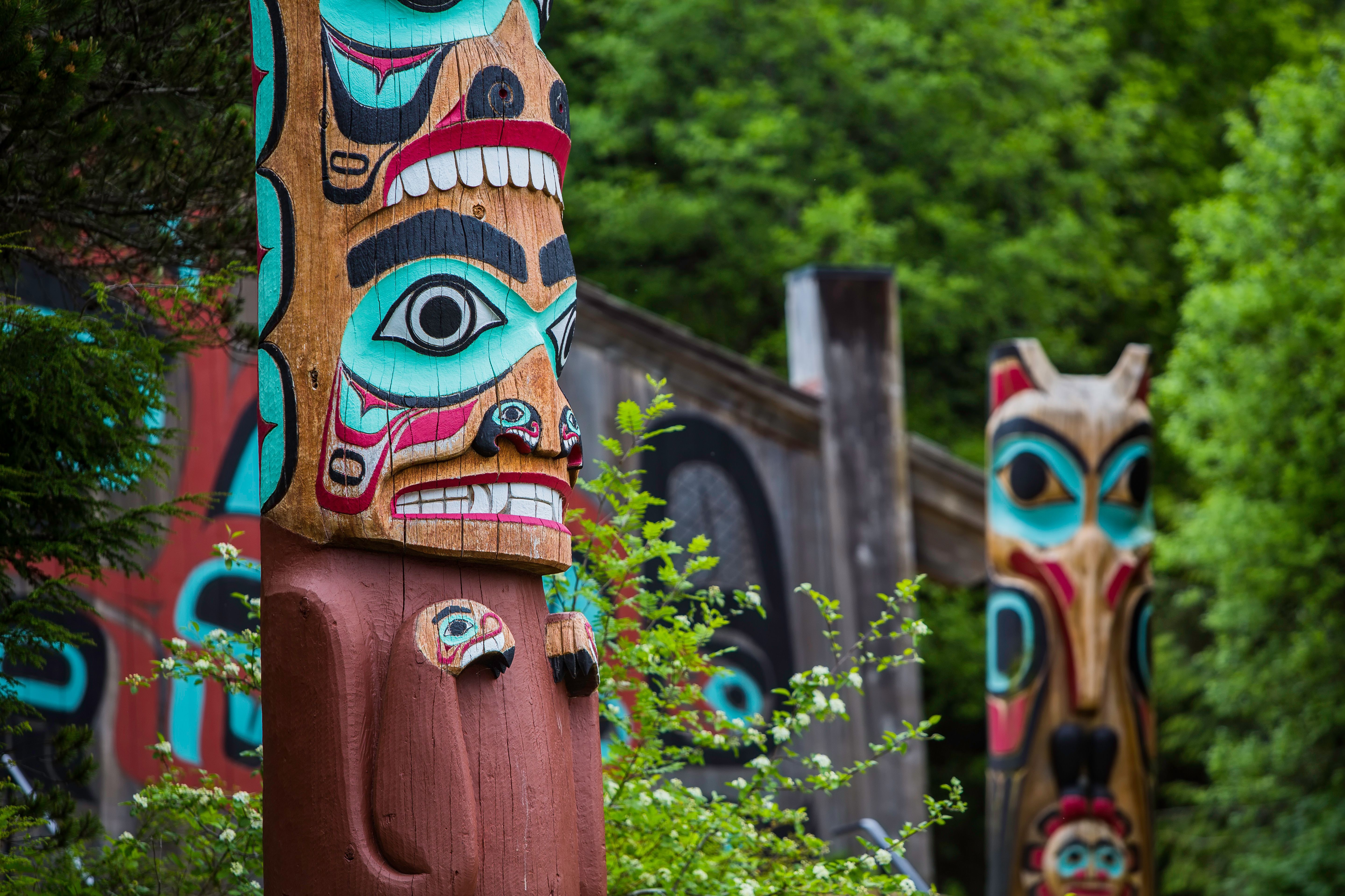 Colorful totem poles surrounded by lush greenery.