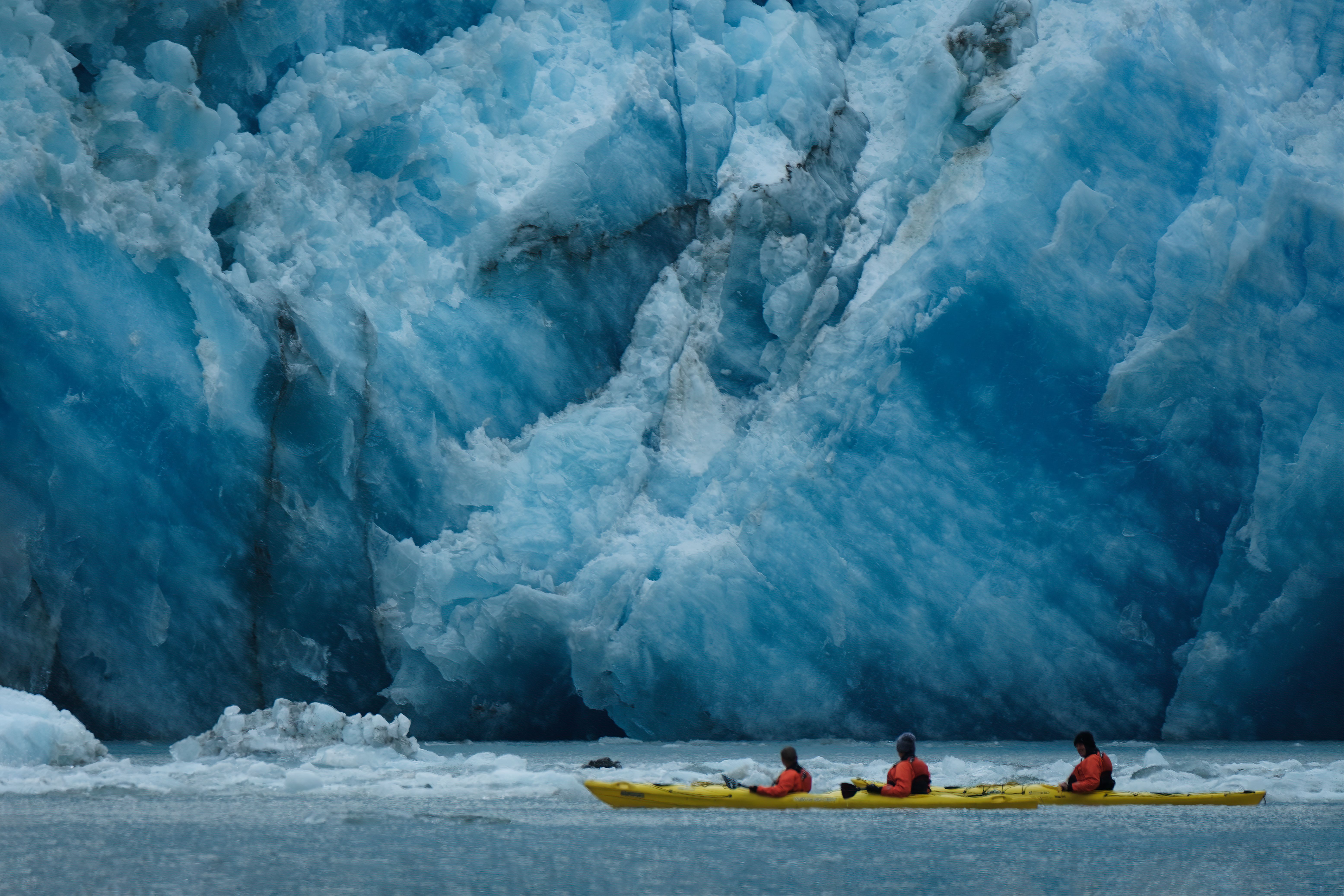 Kayakers exploring icy glacier waters in Alaska.