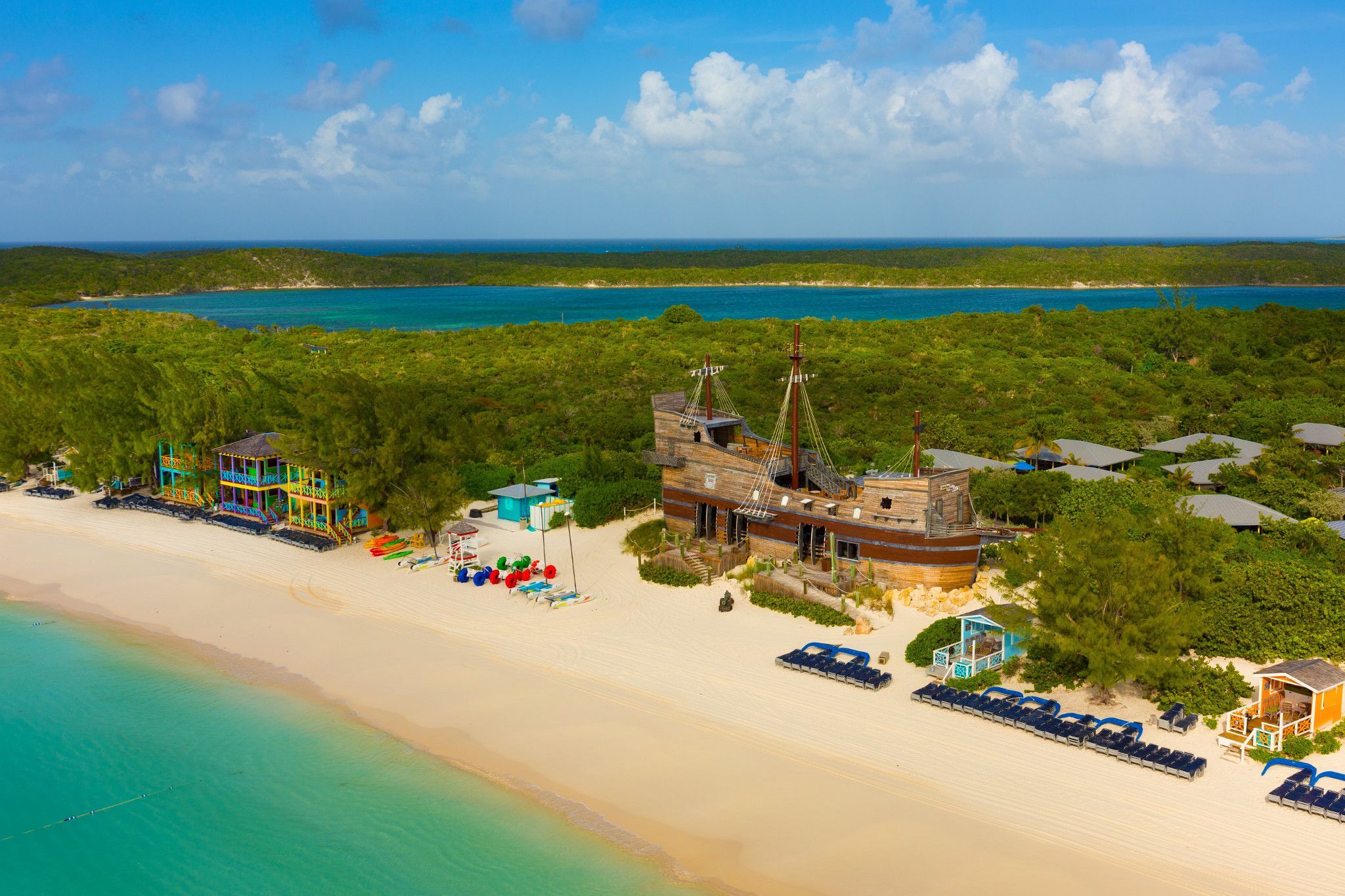 Colorful beachfront with pirate-themed playground and water sports facilities at Half Moon Cay, a private island on Carnival Elation cruises.