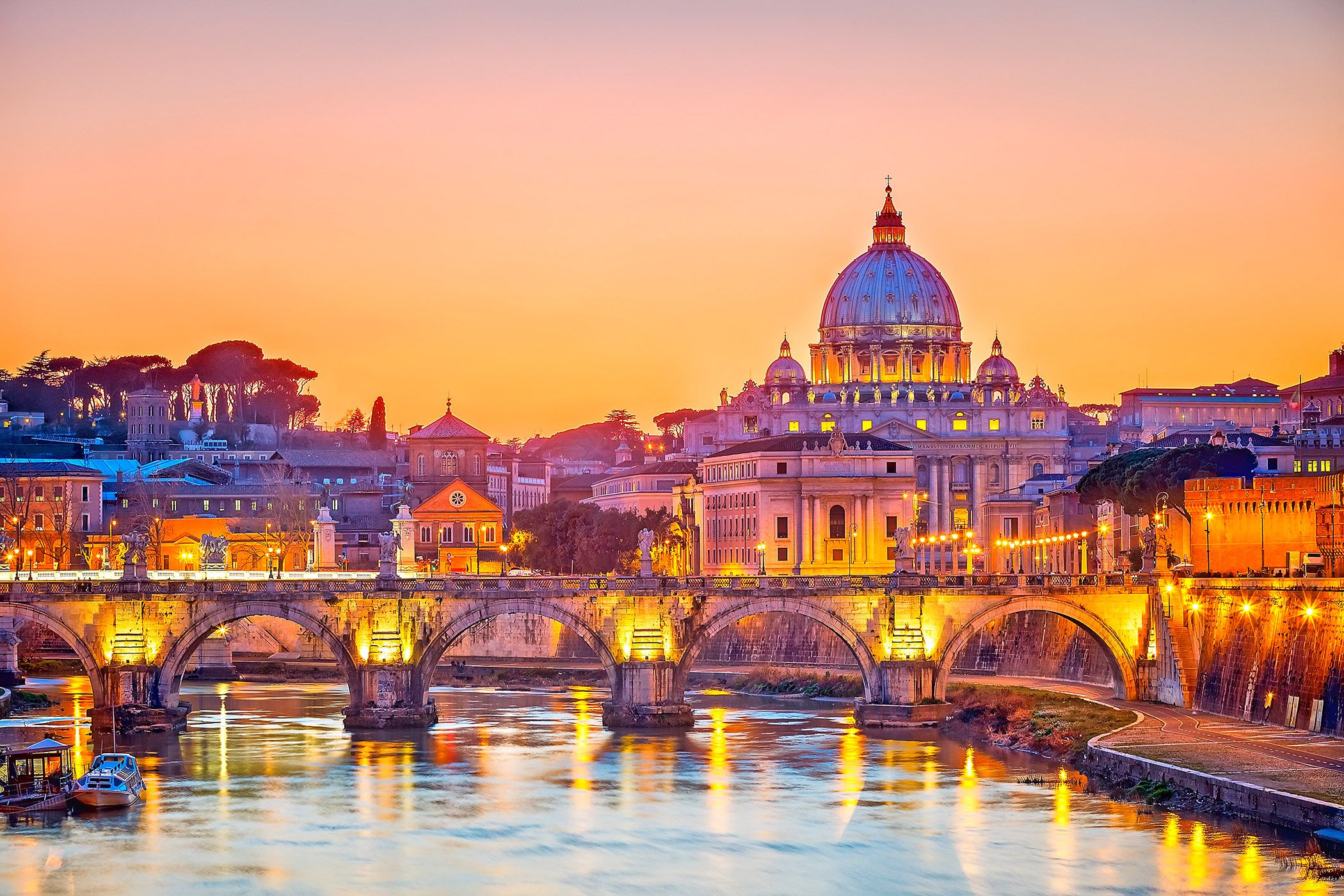 Illuminated St. Peter's Basilica and Sant'Angelo Bridge at sunset in Rome, Italy, a stunning sight on Viking Cruises.