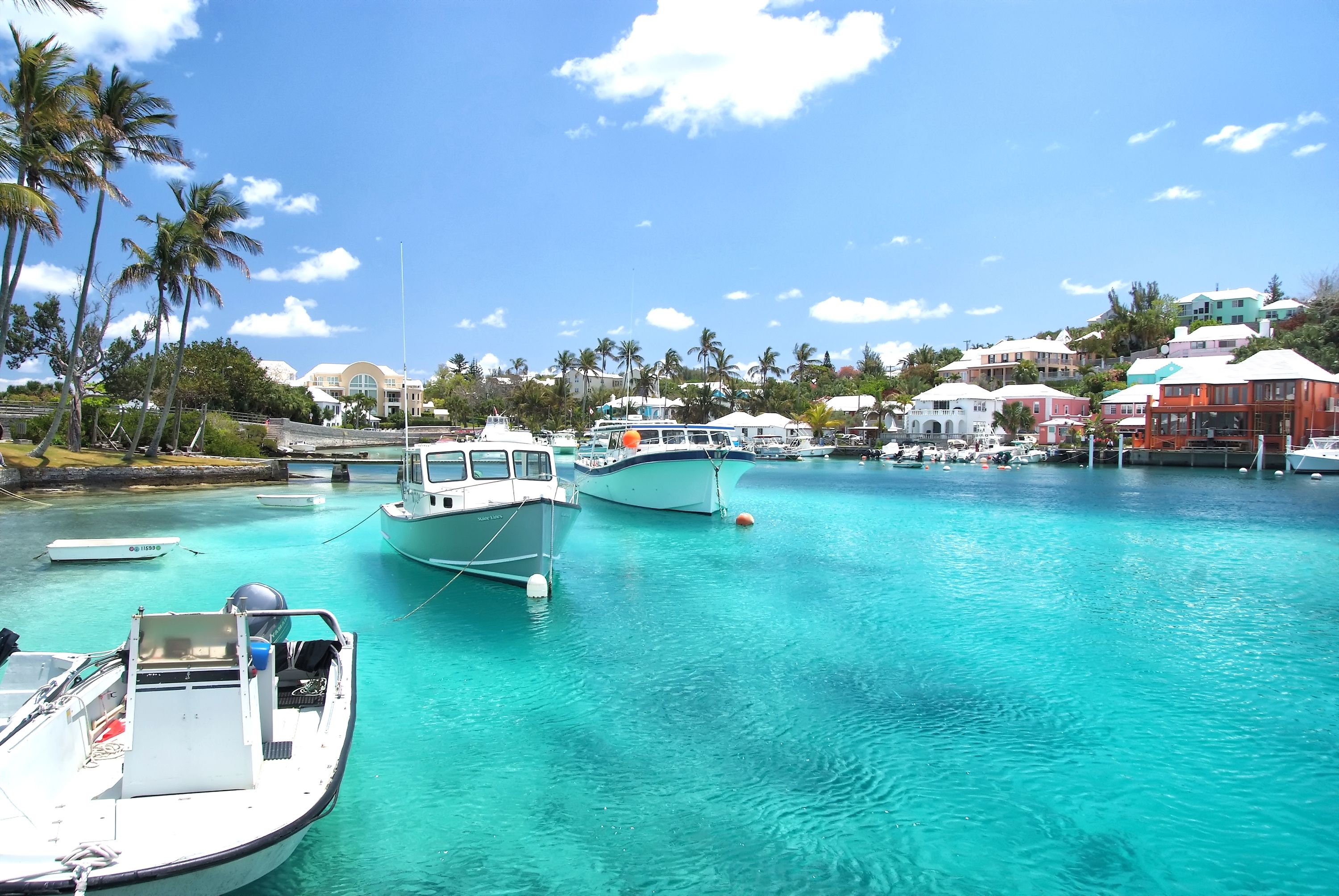 Serene marina in Hamilton, Bermuda, with docked boats and pastel-colored waterfront buildings, a popular Cunard Line destination.