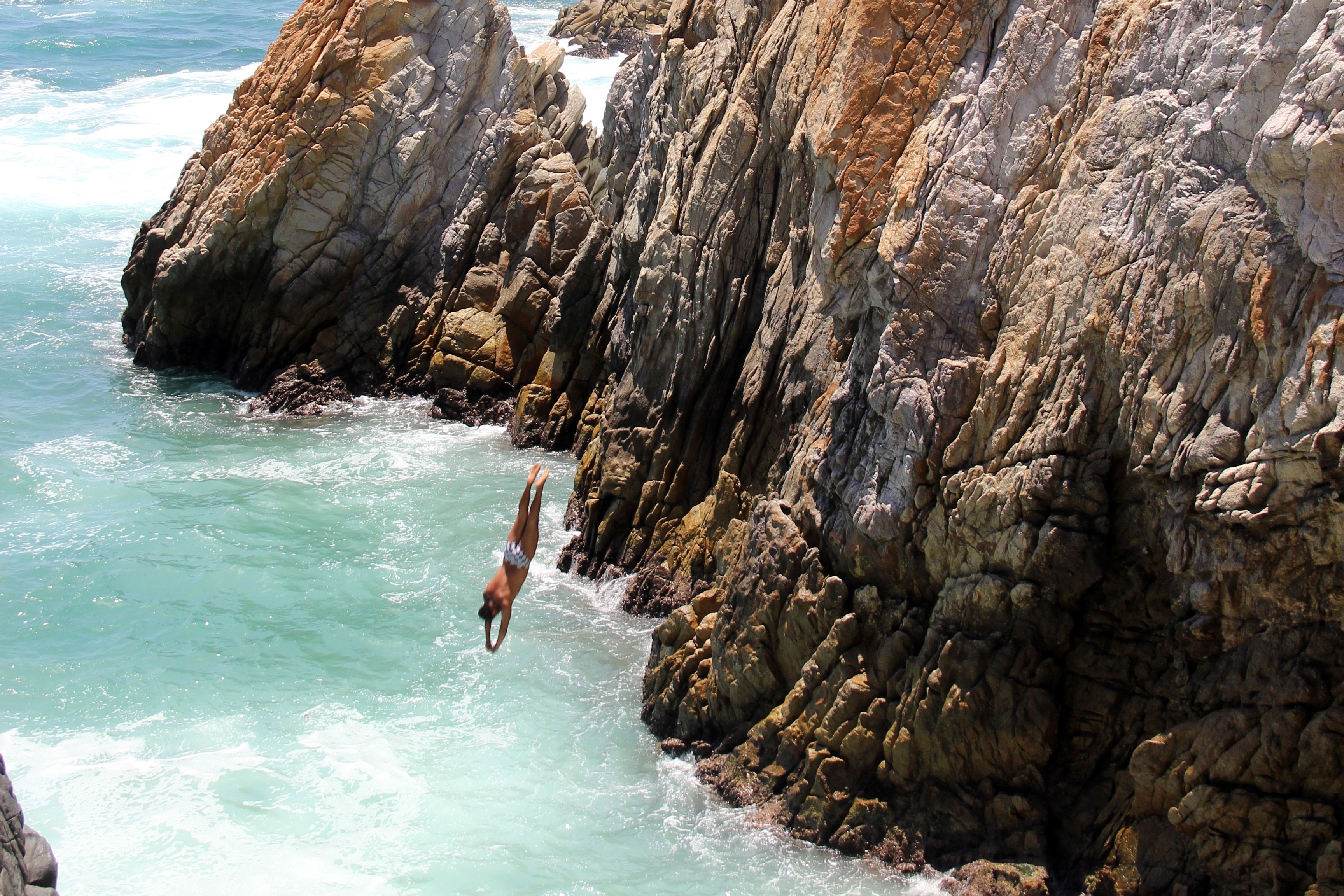 Cliff diver plunges into the turquoise waters at La Quebrada, Acapulco, a thrilling shore excursion on Oceania Cruises.