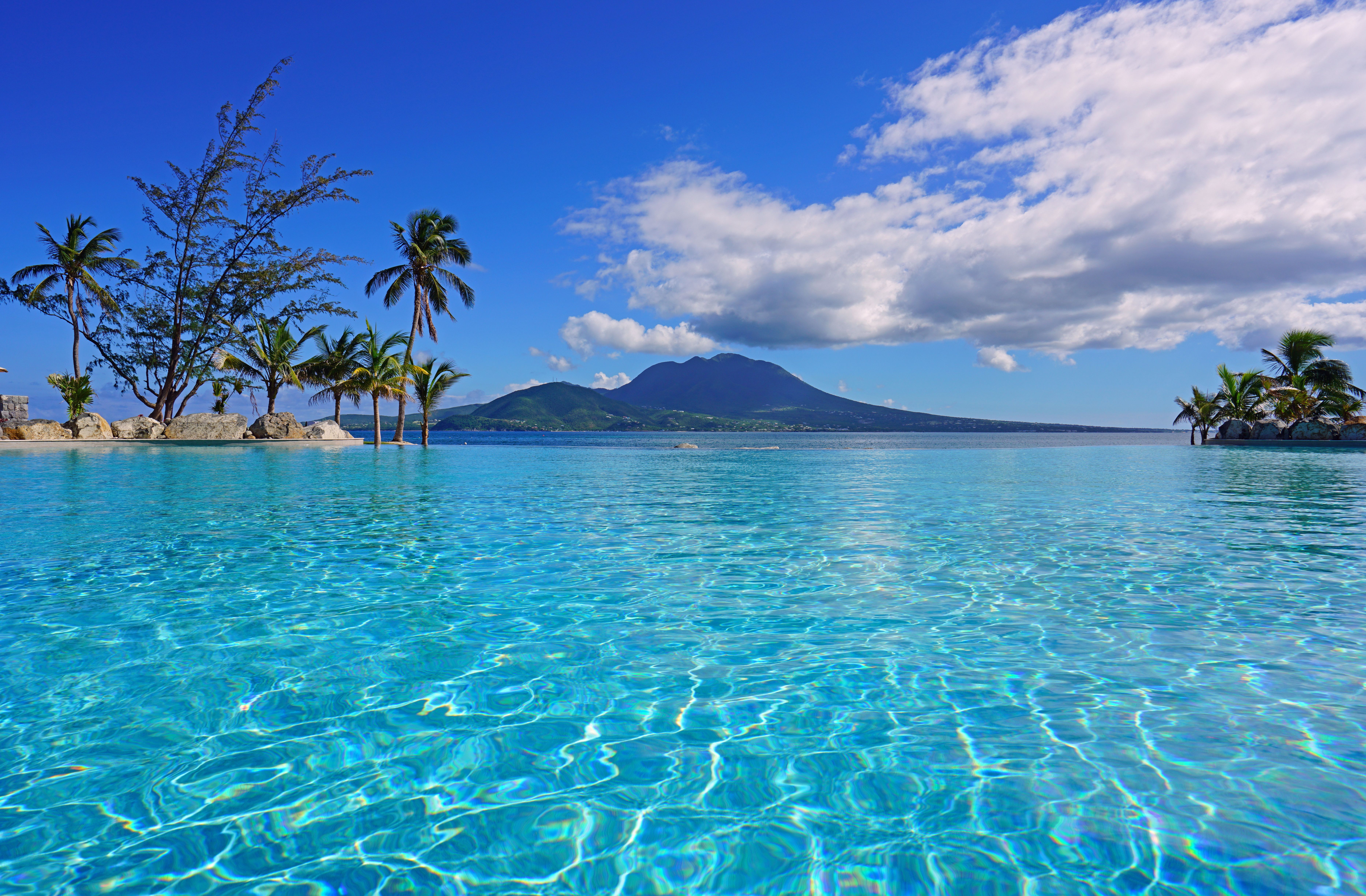 Crystal clear waters of Banana Bay Beach, St. Kitts, with palm trees and a scenic backdrop of Nevis.