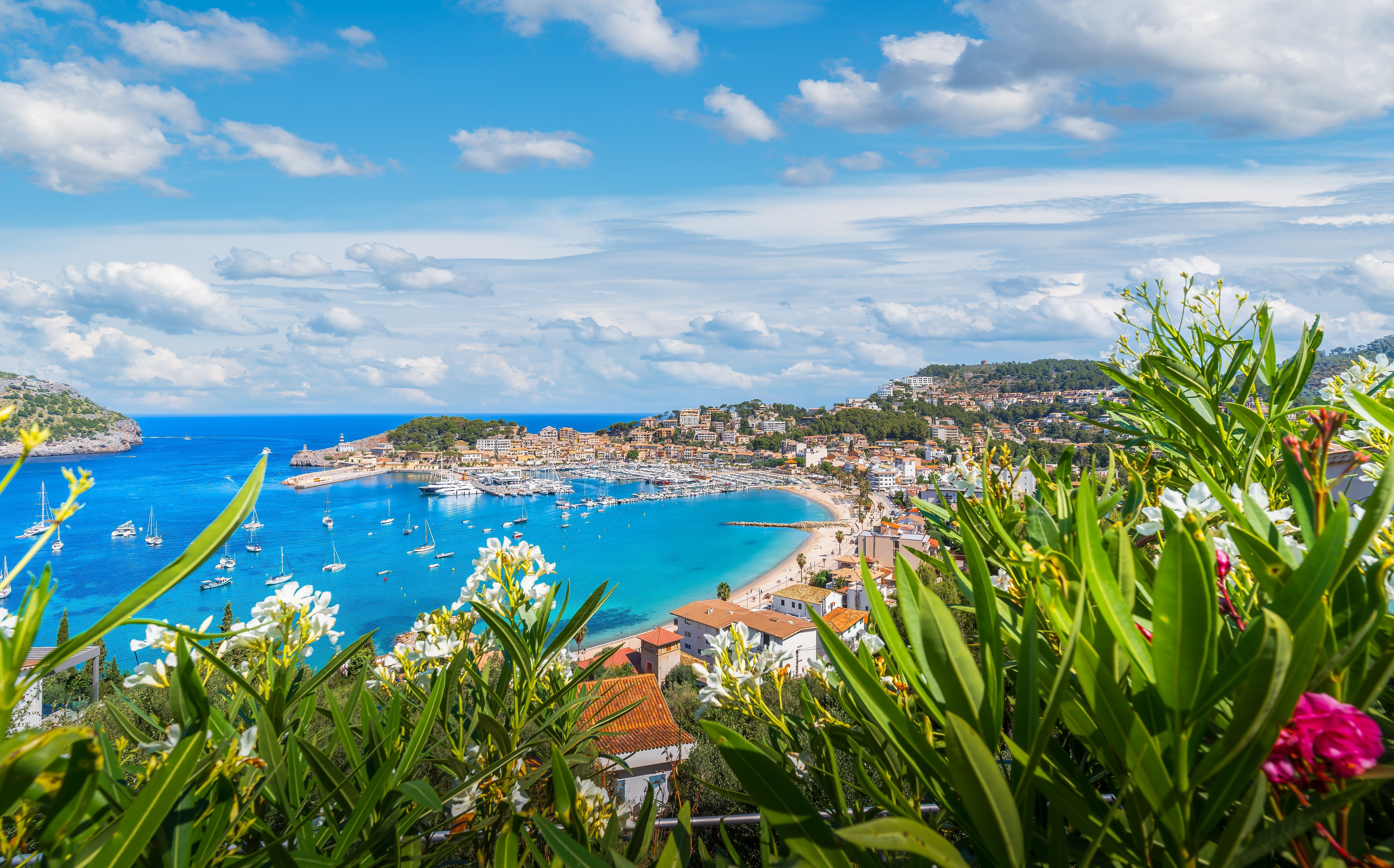 Scenic Port de Sóller with marina, sandy beach, and lush hills surrounding the bay in Mallorca, Spain.