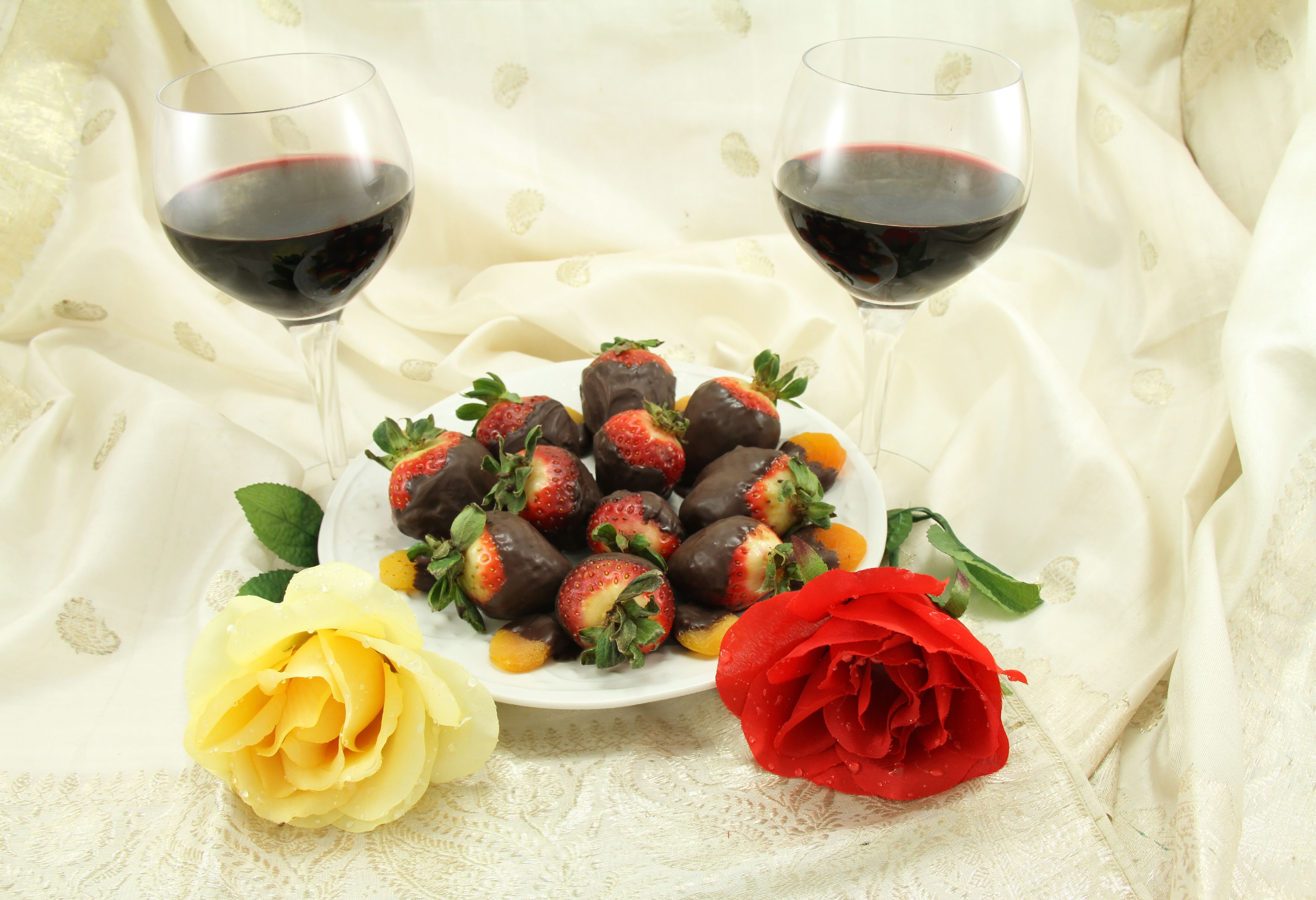 Plate of chocolate-covered strawberries with two glasses of red wine, romantic cruise dessert, luxury cruise dining.