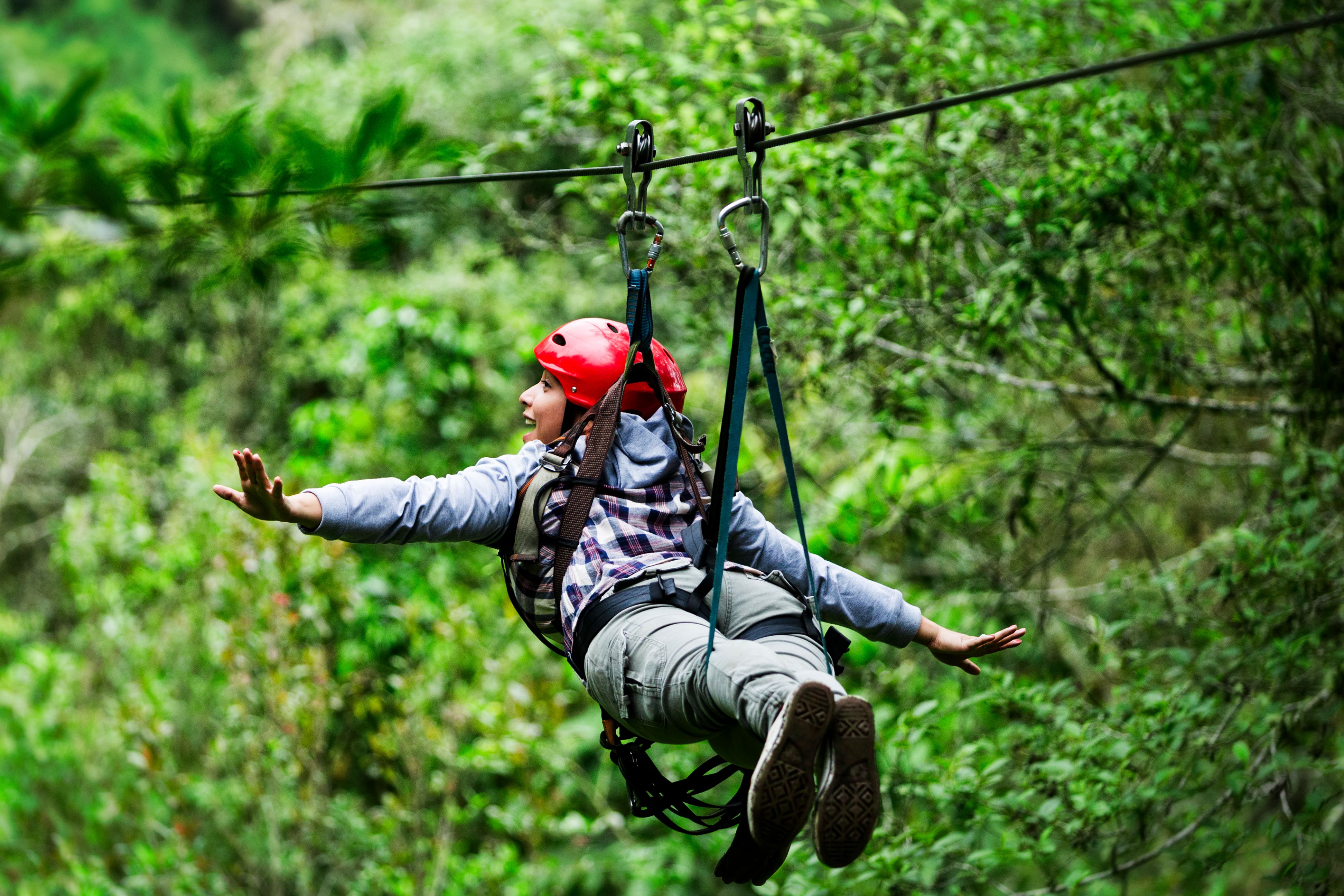 Adventurer soaring through lush rainforest on a zipline, an exhilarating outdoor activity popular on South Pacific or Caribbean cruise excursions.