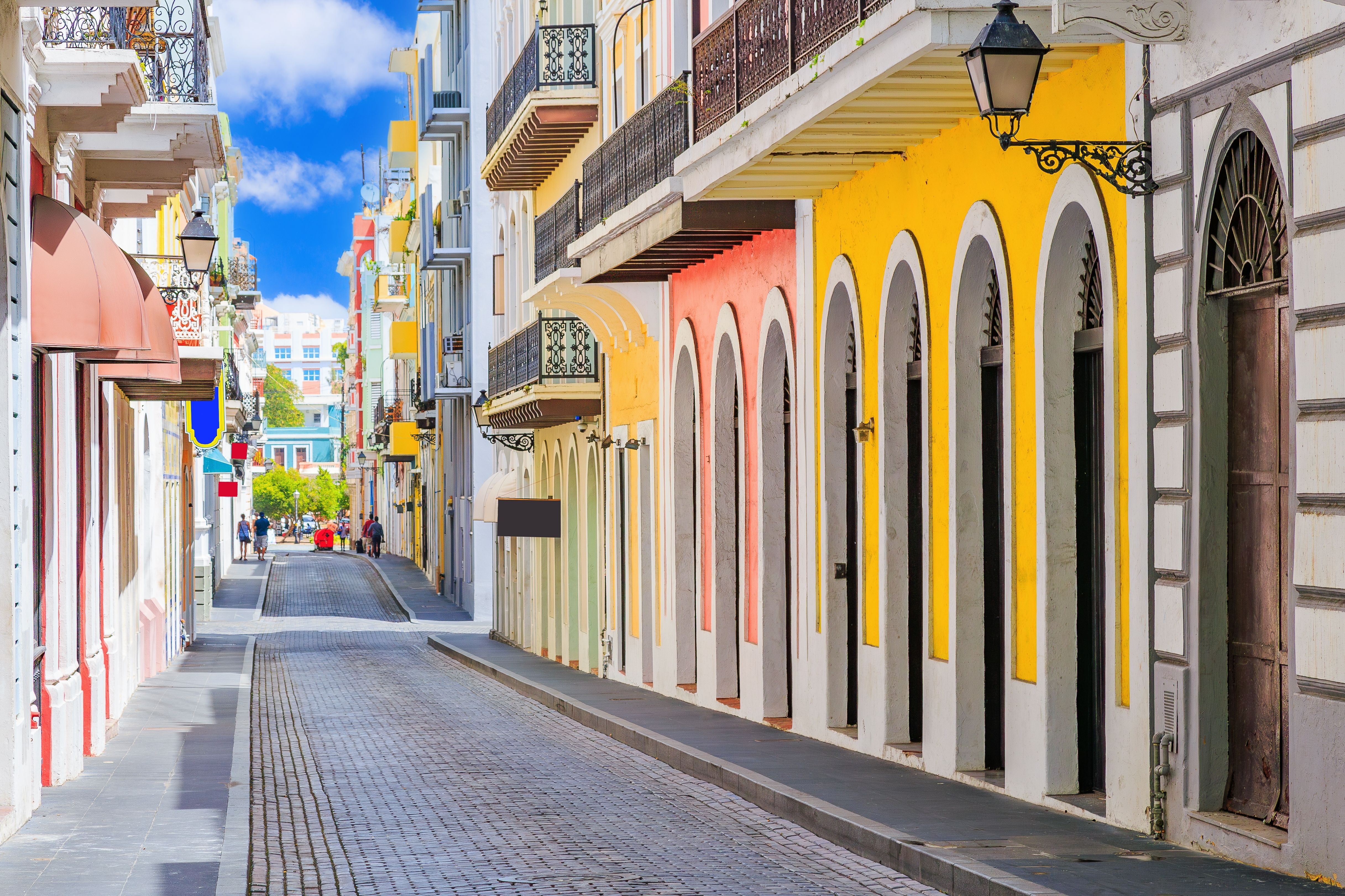 Charming cobblestone street in Old San Juan, Puerto Rico, featuring colorful colonial-style buildings with balconies and arched windows.