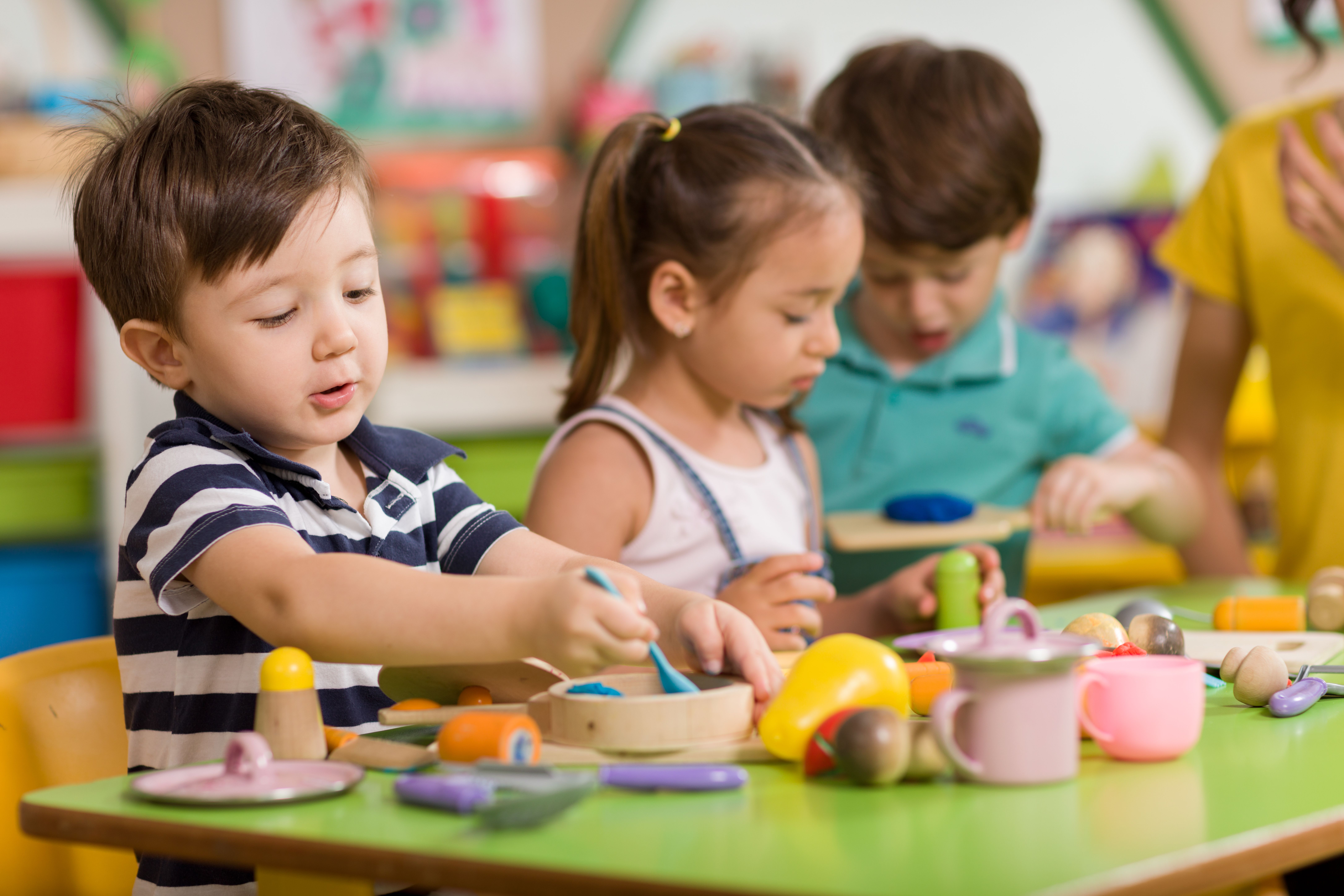 Young children engaged in creative play at a kids' club onboard a cruise ship, surrounded by colorful toys and an interactive learning environment.