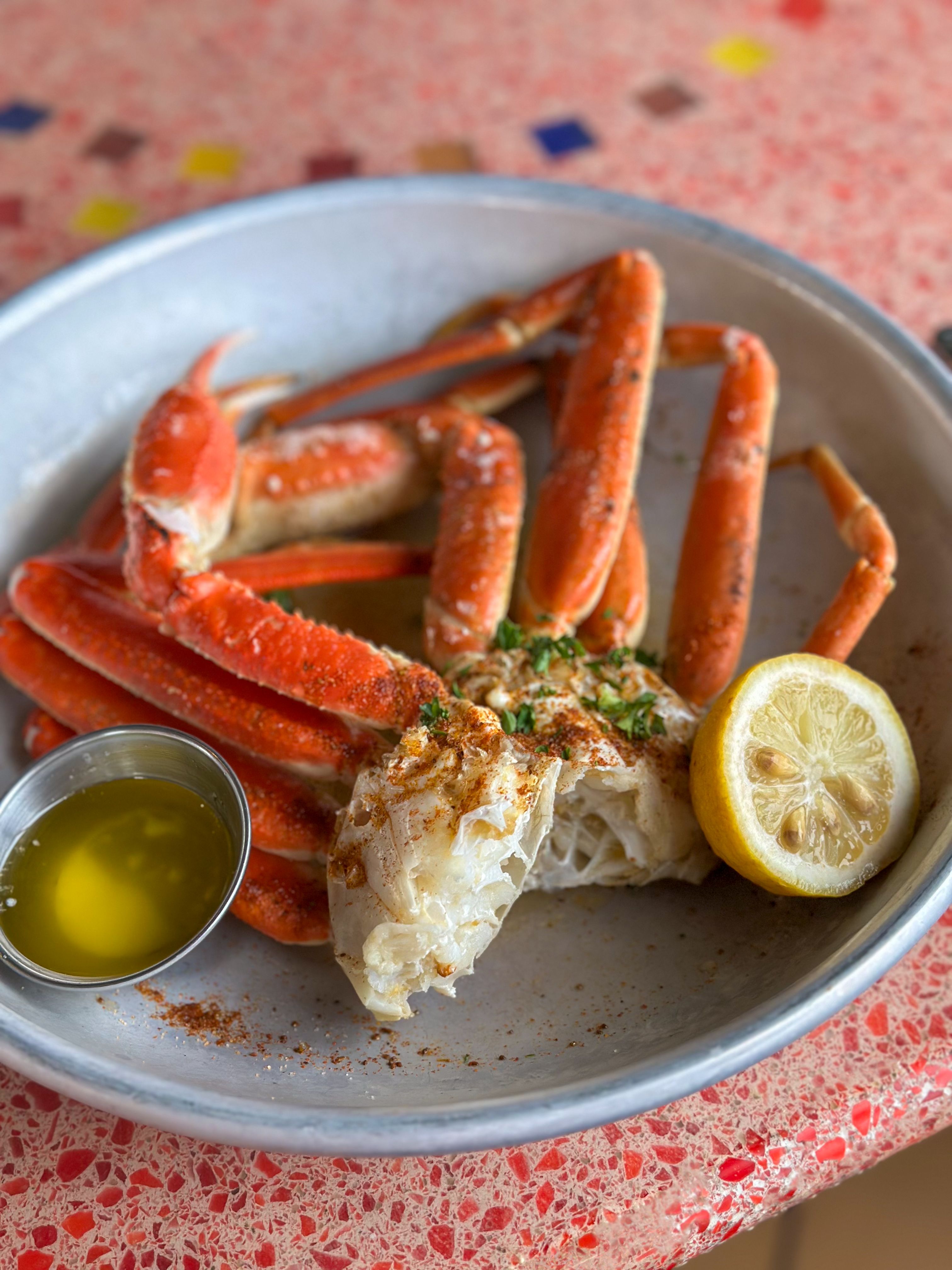 Freshly steamed snow crab legs served with melted butter and a lemon wedge at the Carnival Conquest's Seafood Shack, offering a delicious seafood experience at sea.