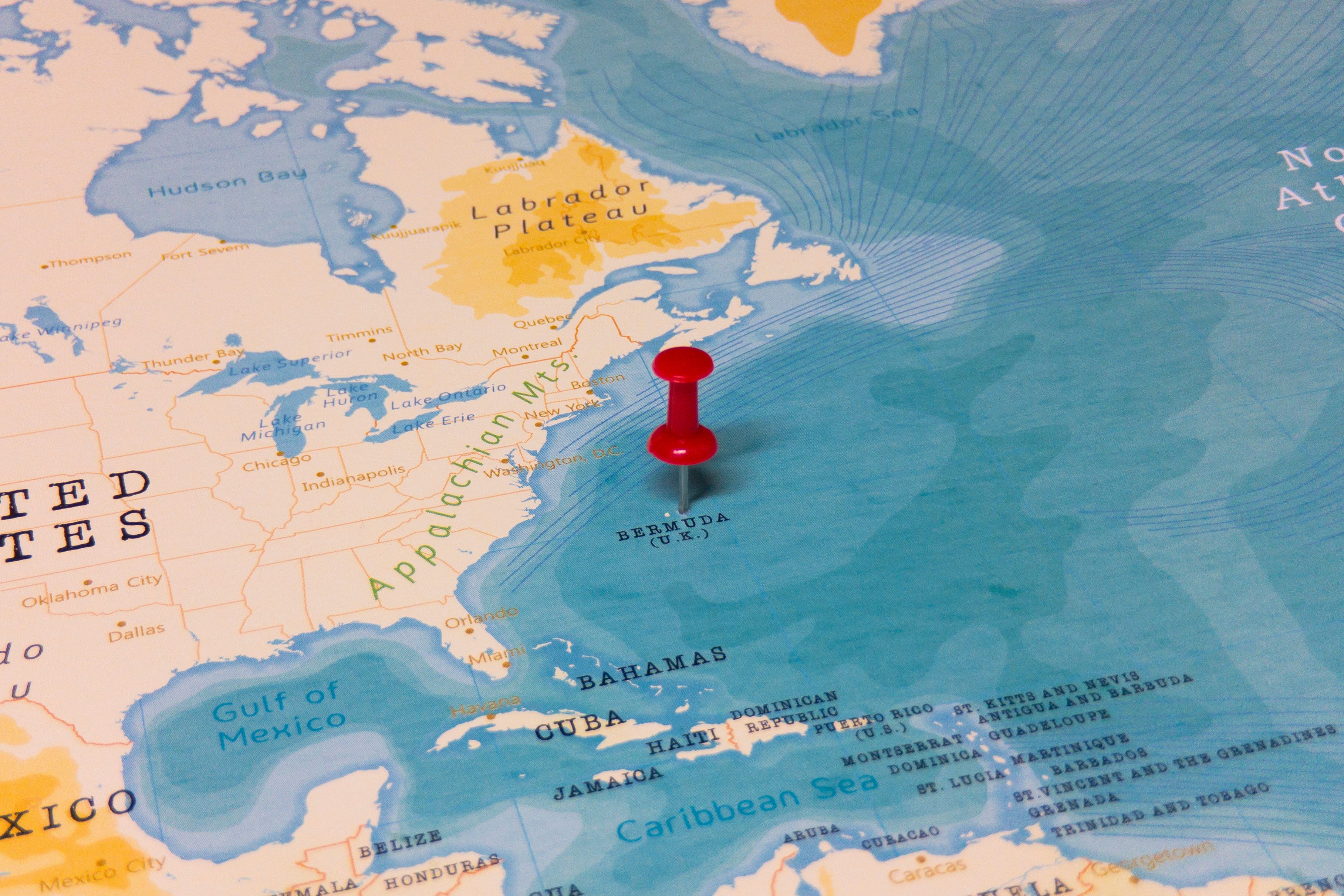 A map highlighting Bermuda's location in the Atlantic Ocean with a red pushpin, showing its proximity to the East Coast of the United States, including New York and Florida.