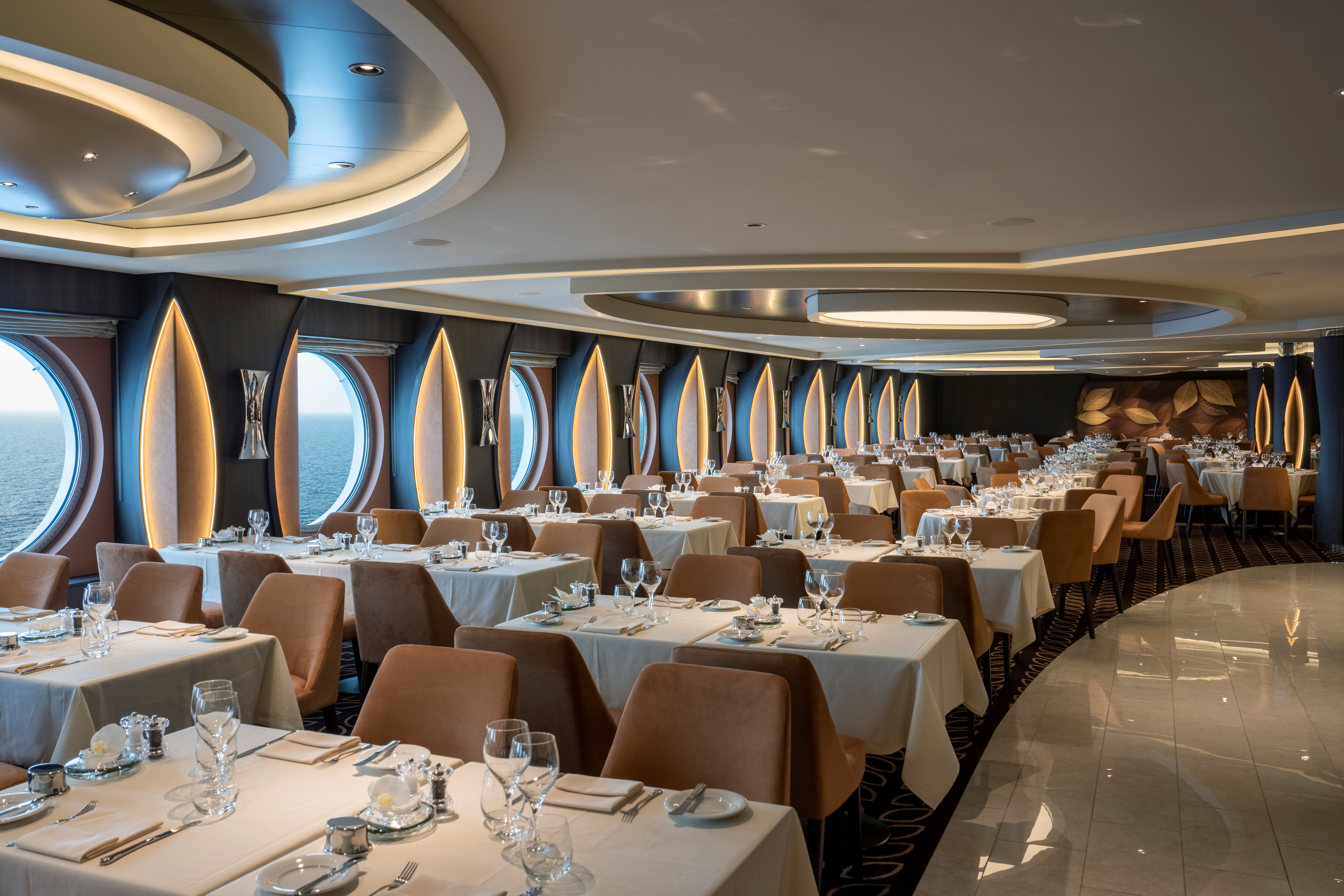 La Foglia Restaurant on MSC World America, featuring elegant decor, ocean-view portholes, and ambient lighting for a refined cruise dining experience.