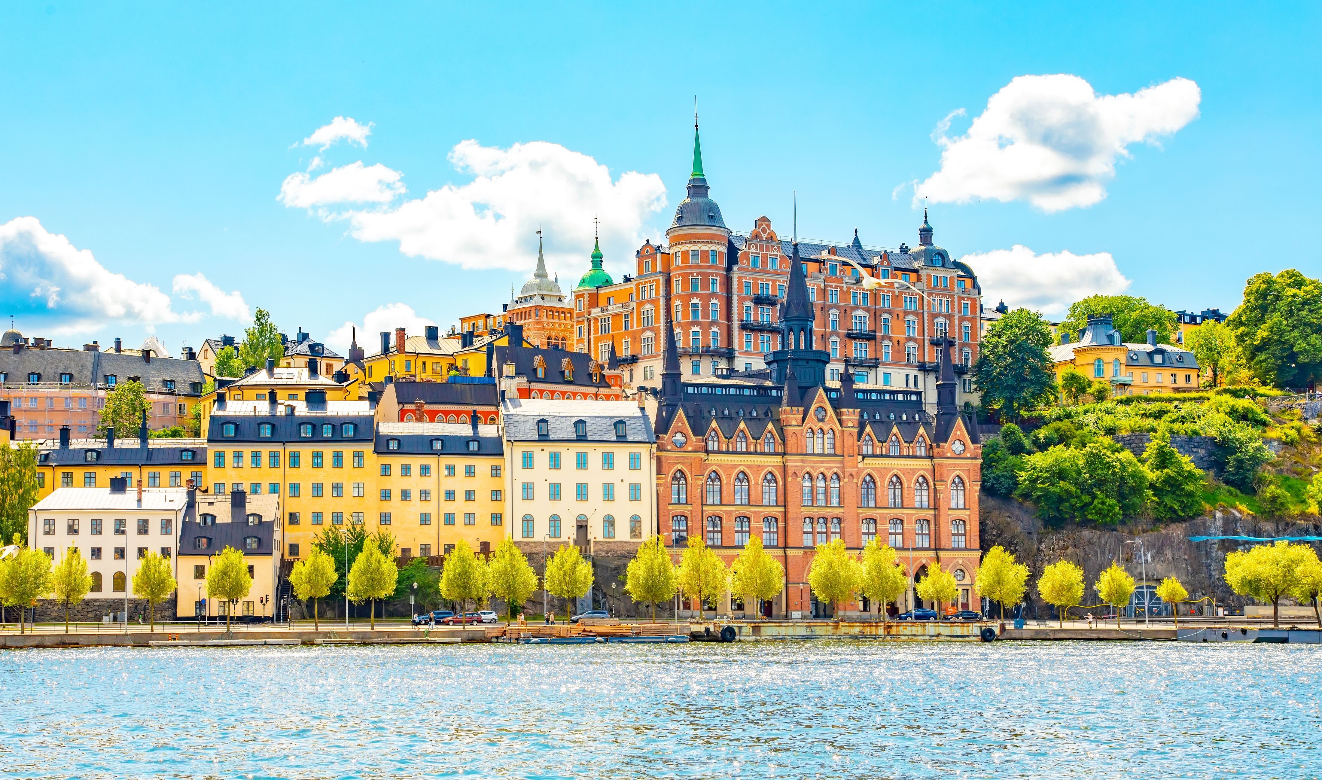 Colorful historic buildings along the waterfront in Stockholm, Sweden, with vibrant architecture and lush greenery.