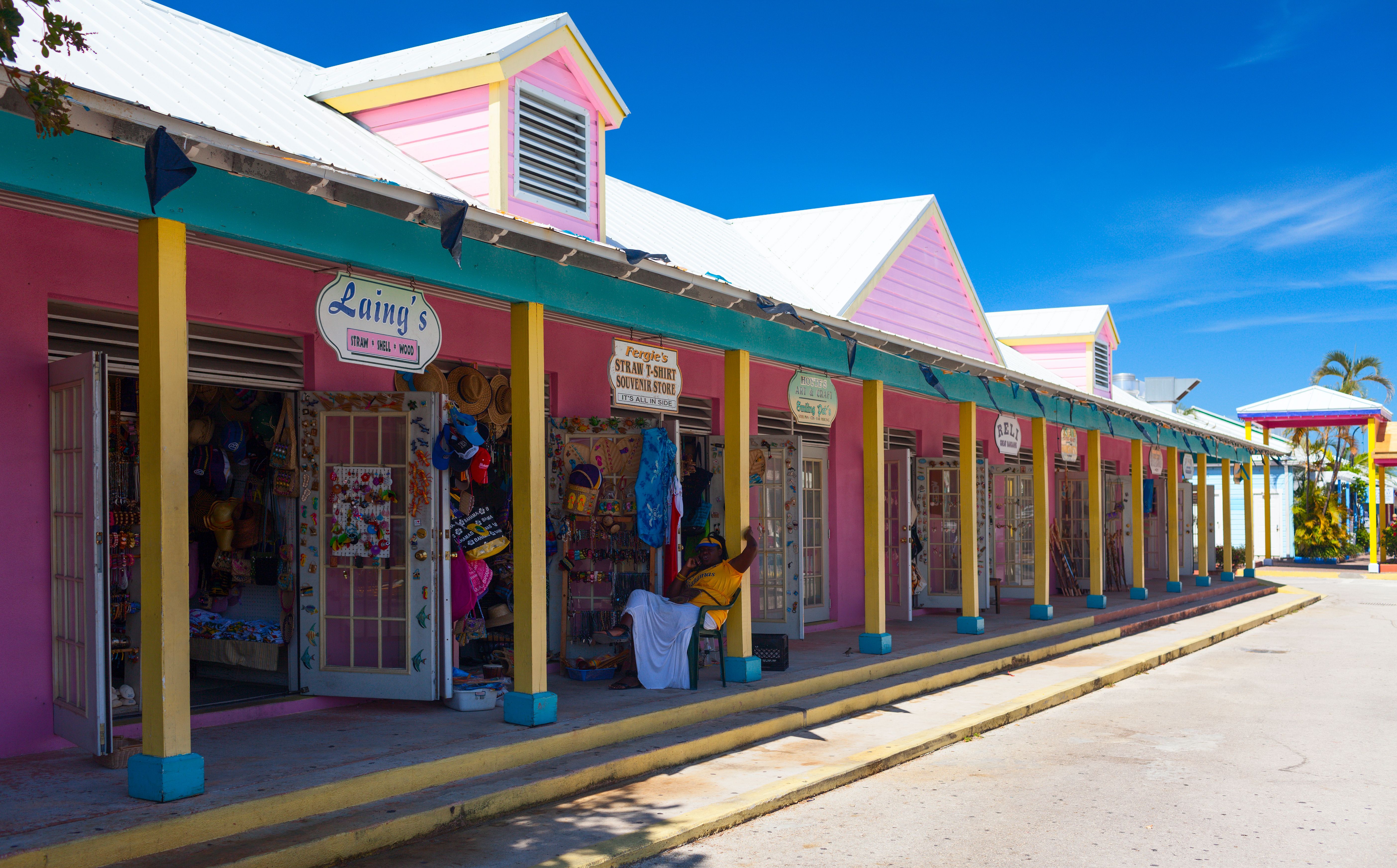 Colorful shops at Port Lucaya Marketplace in Freeport, Bahamas, with vibrant pink and yellow facades, offering local crafts and souvenirs.