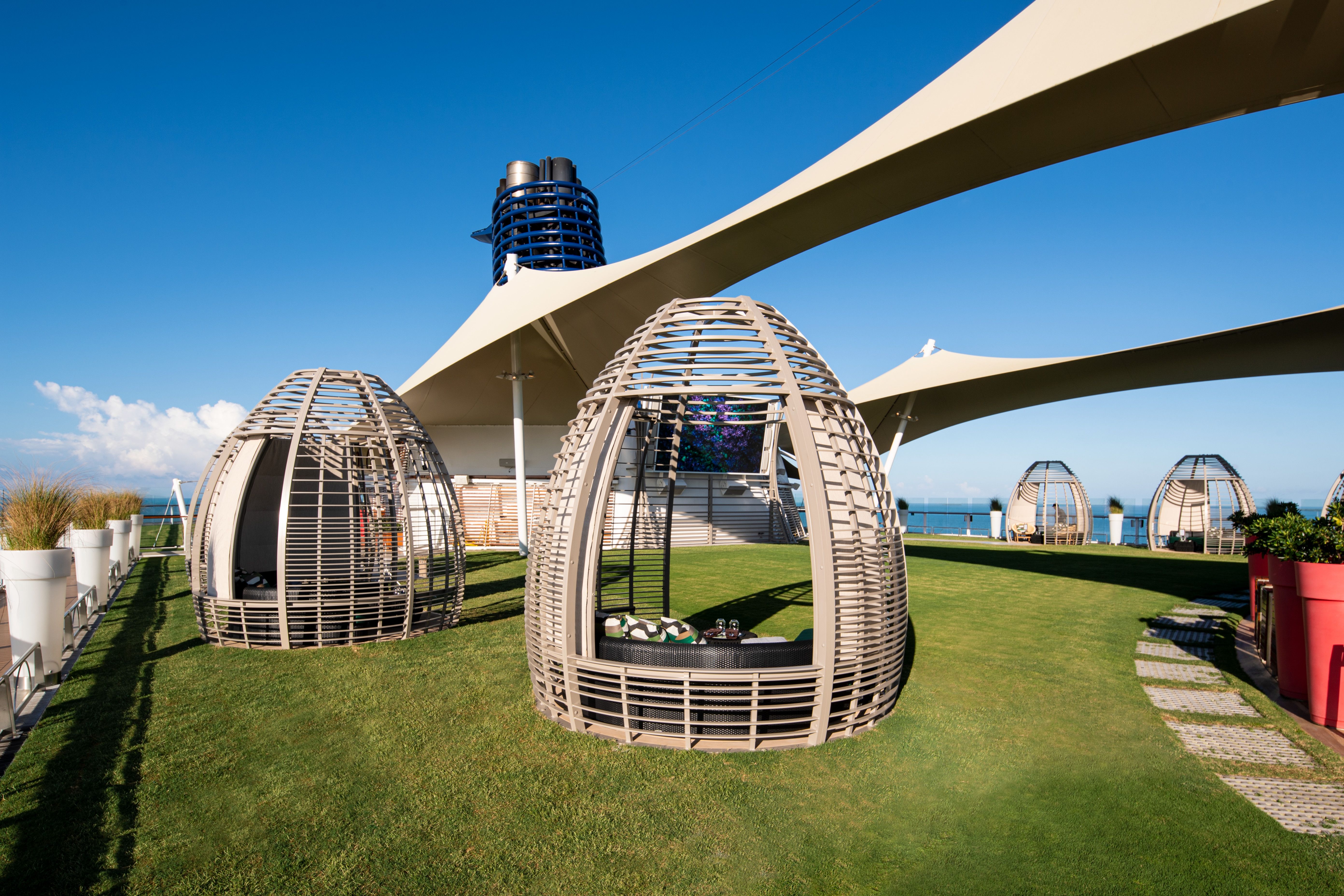 Lawn Club on a Celebrity cruise ship with lush grass, modern cabanas, and ocean views, offering a relaxing outdoor retreat.