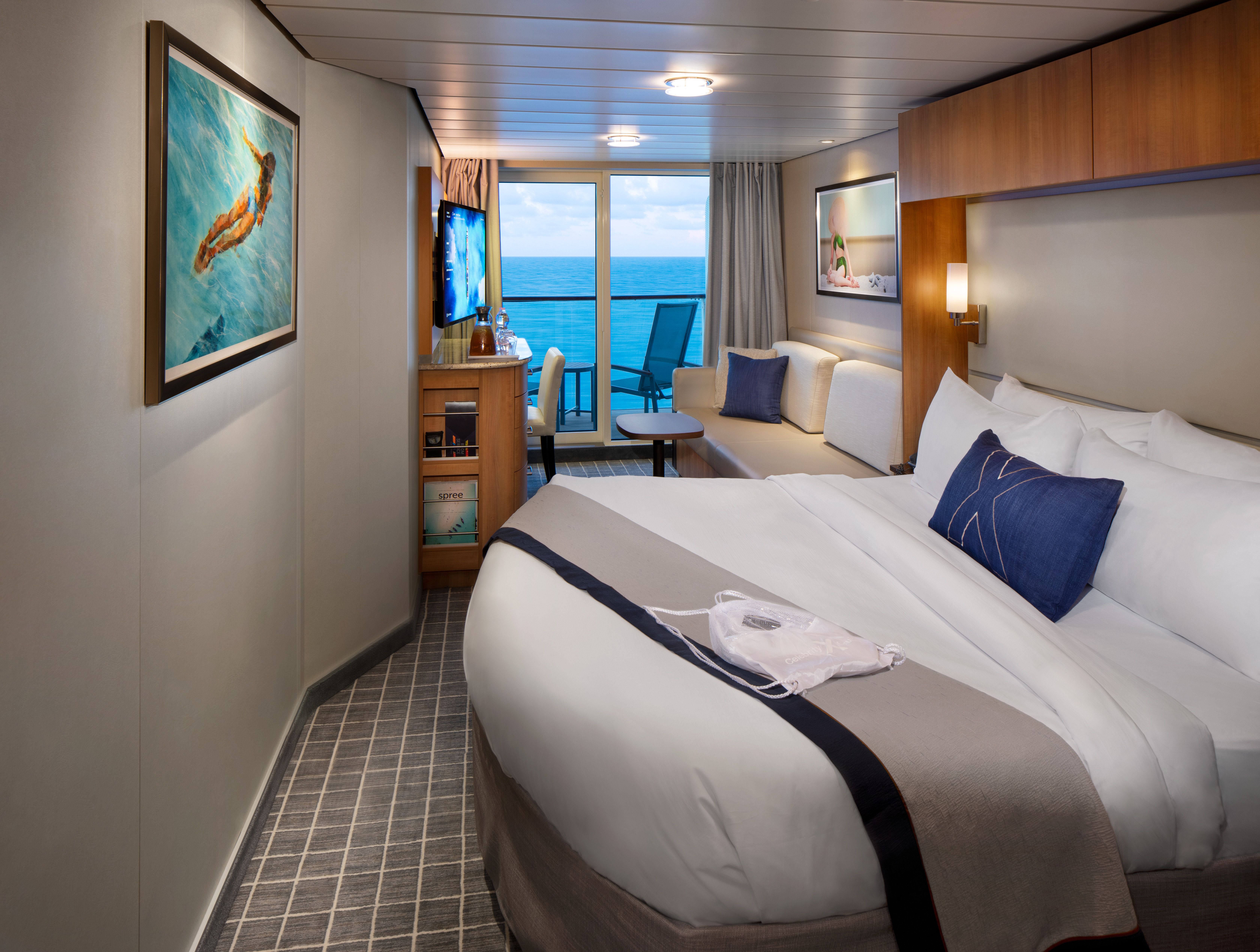 Aqua Class cabin on a Celebrity cruise ship with a king-size bed, private balcony, and ocean views, offering a serene, spa-like experience.