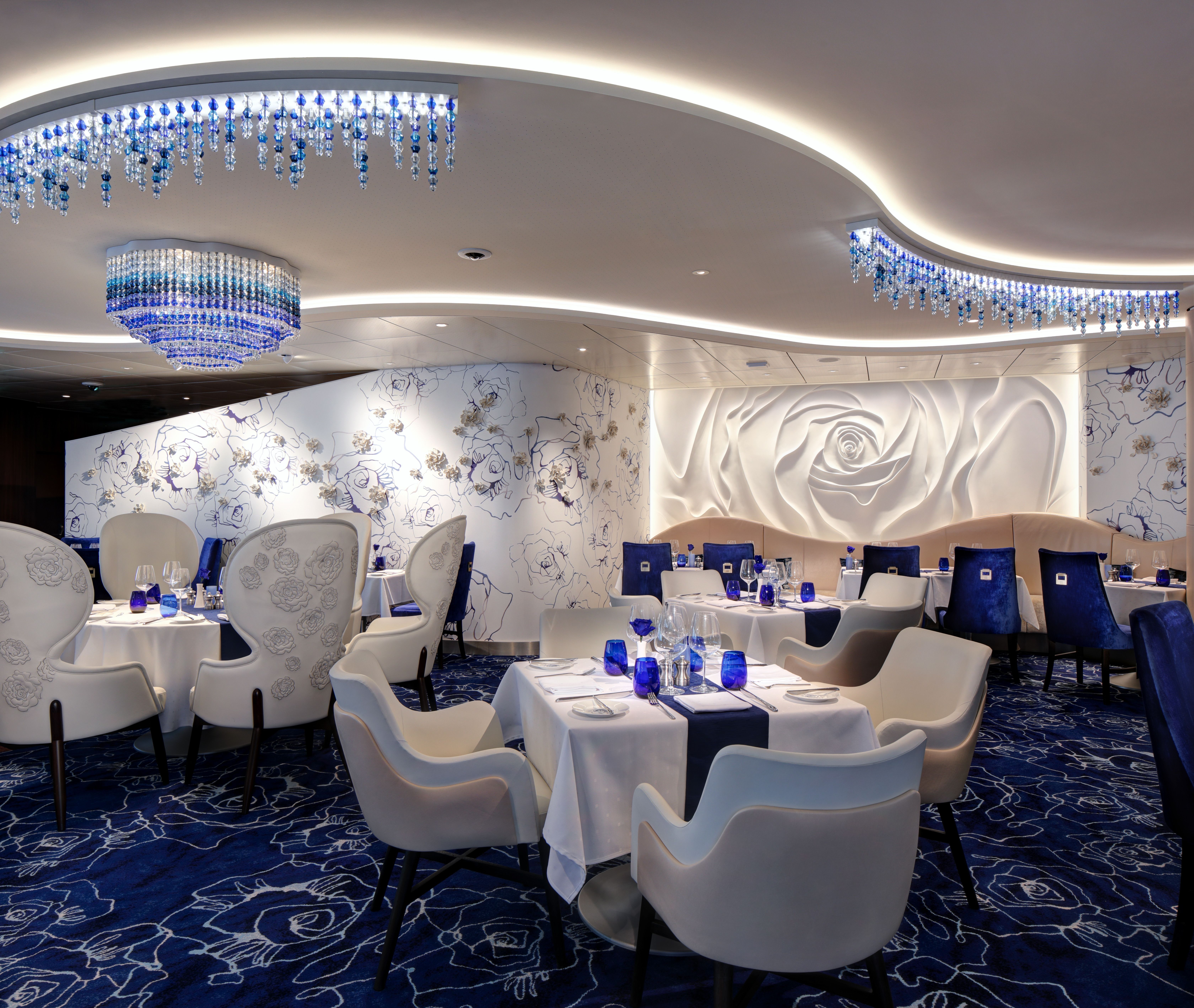 Blu restaurant on a Celebrity cruise ship featuring elegant white and blue décor, crystal chandeliers, and a sophisticated atmosphere for Aqua Class guests.