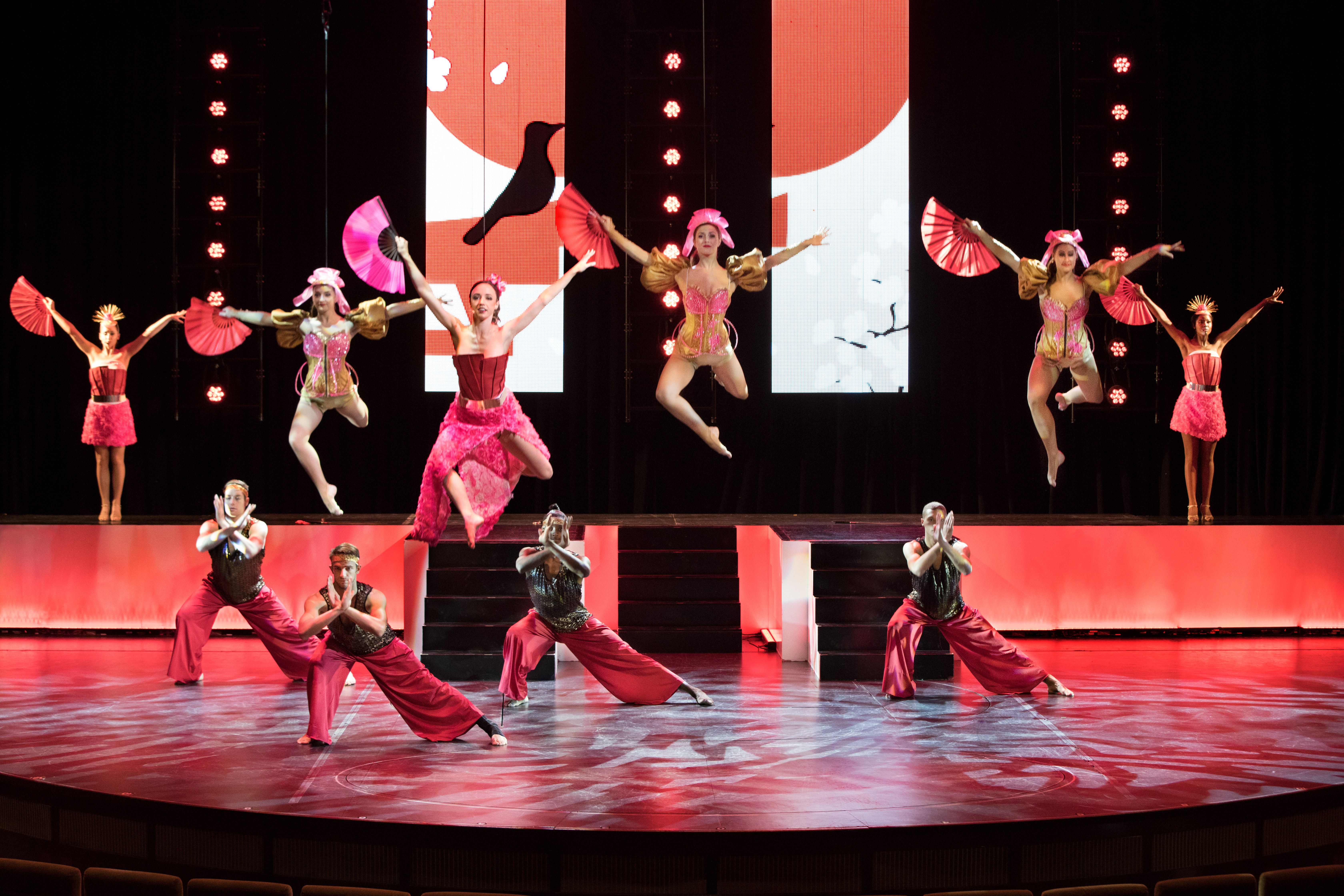 Live entertainment on a Celebrity cruise ship with vibrant costumes, dancers, and dynamic stage lighting.