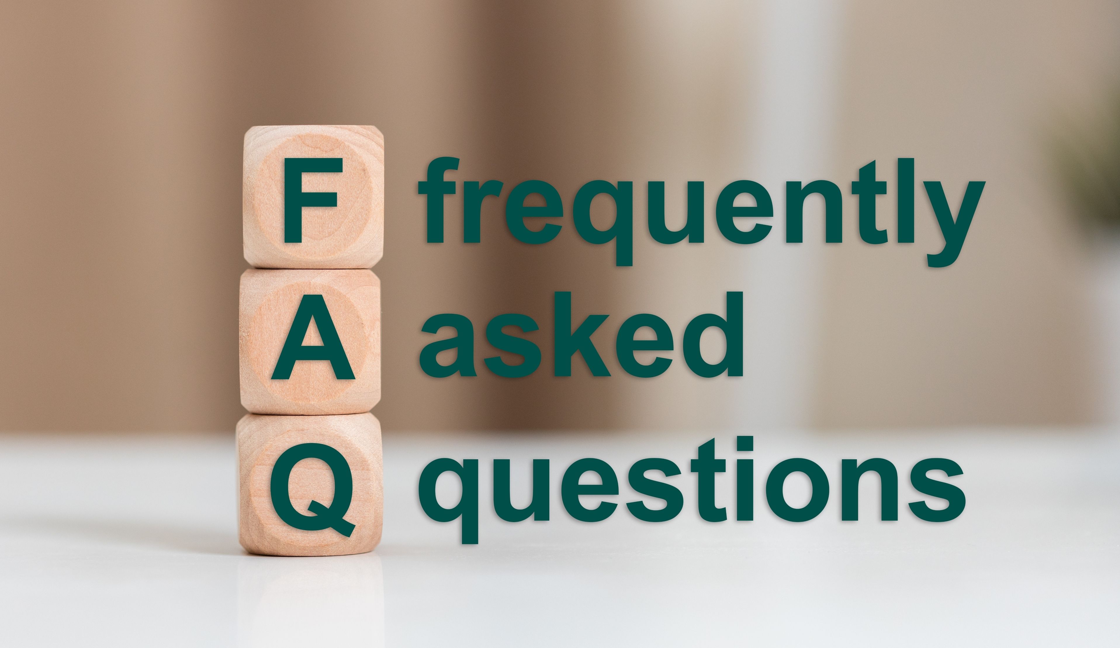Wooden blocks stacked vertically spell out "FAQ" beside the words "frequently asked questions" in bold green text on a blurred beige background.